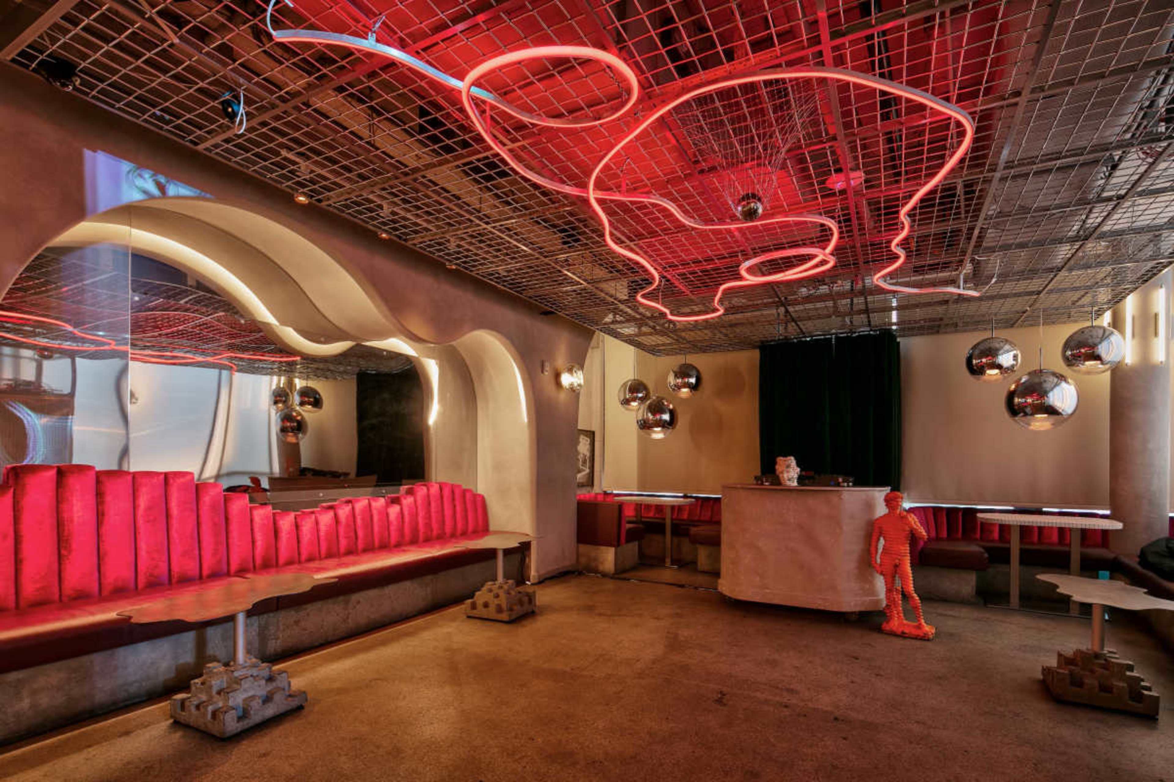 The image features a modern restaurant interior with red neon lighting, curved seating, and metallic decor elements.