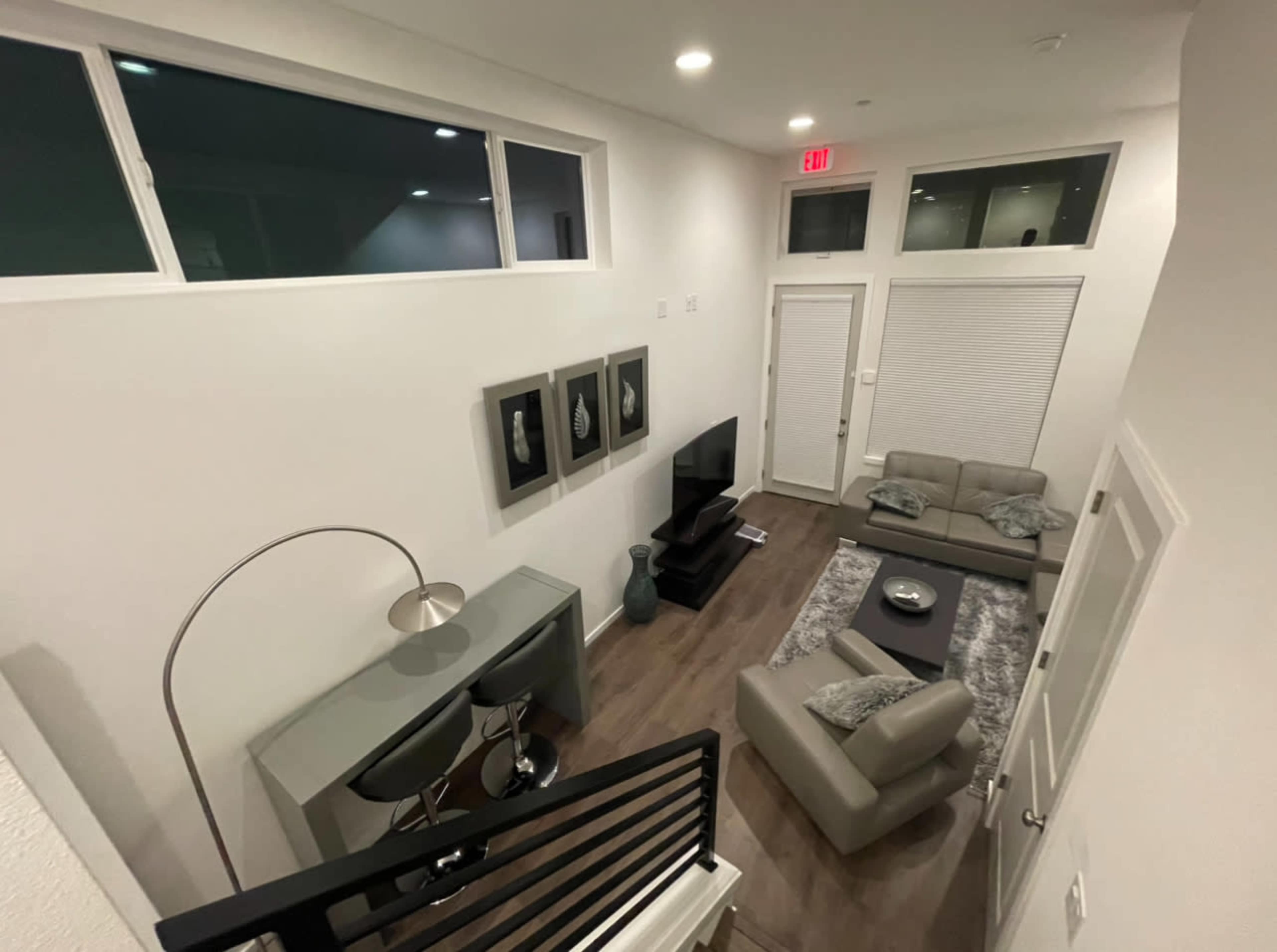 A modern living room with a sofa set, a coffee table, and a television, all arranged around a light gray rug.
