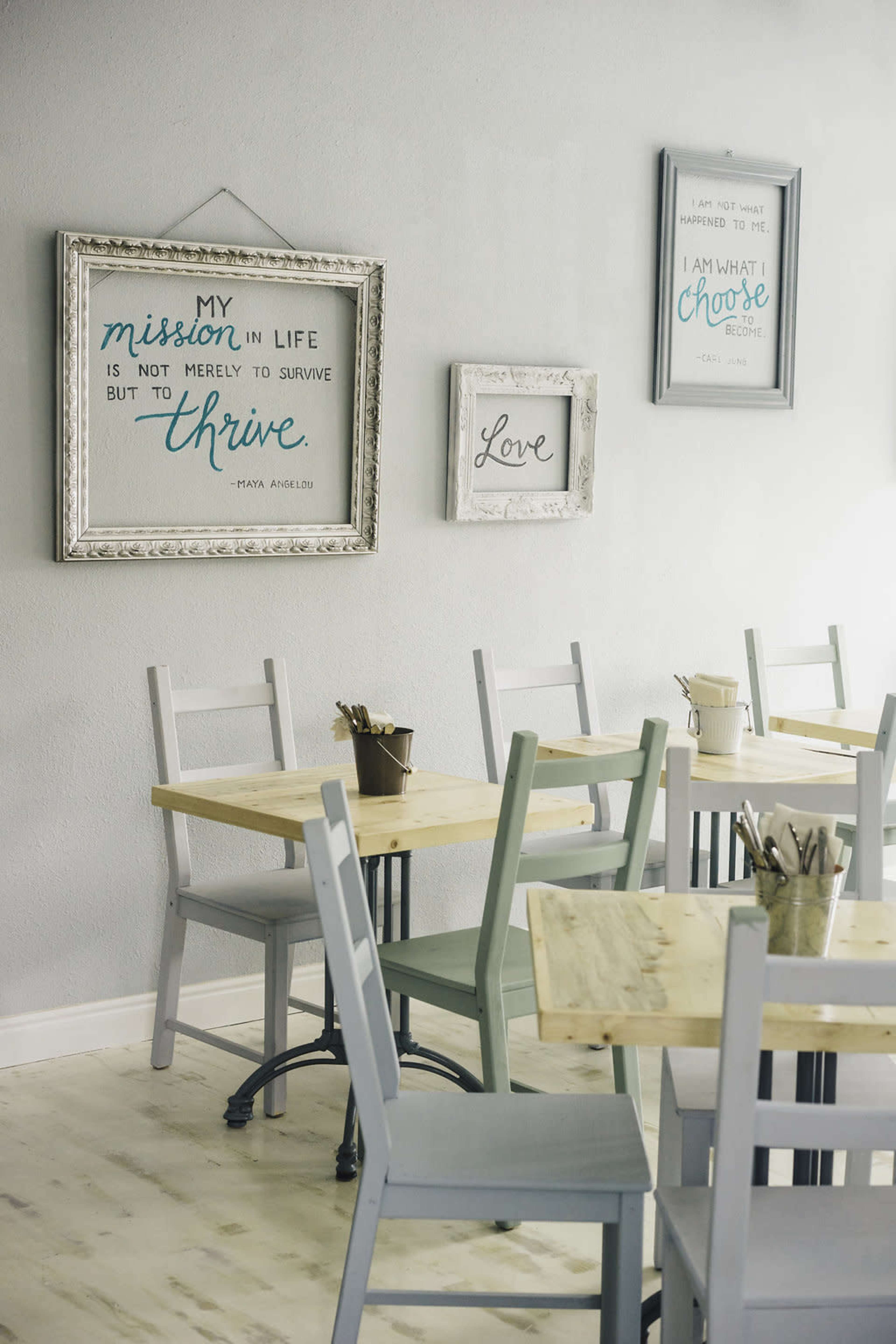 A cozy café interior featuring wooden tables and chairs, with inspirational quotes framed on the walls.