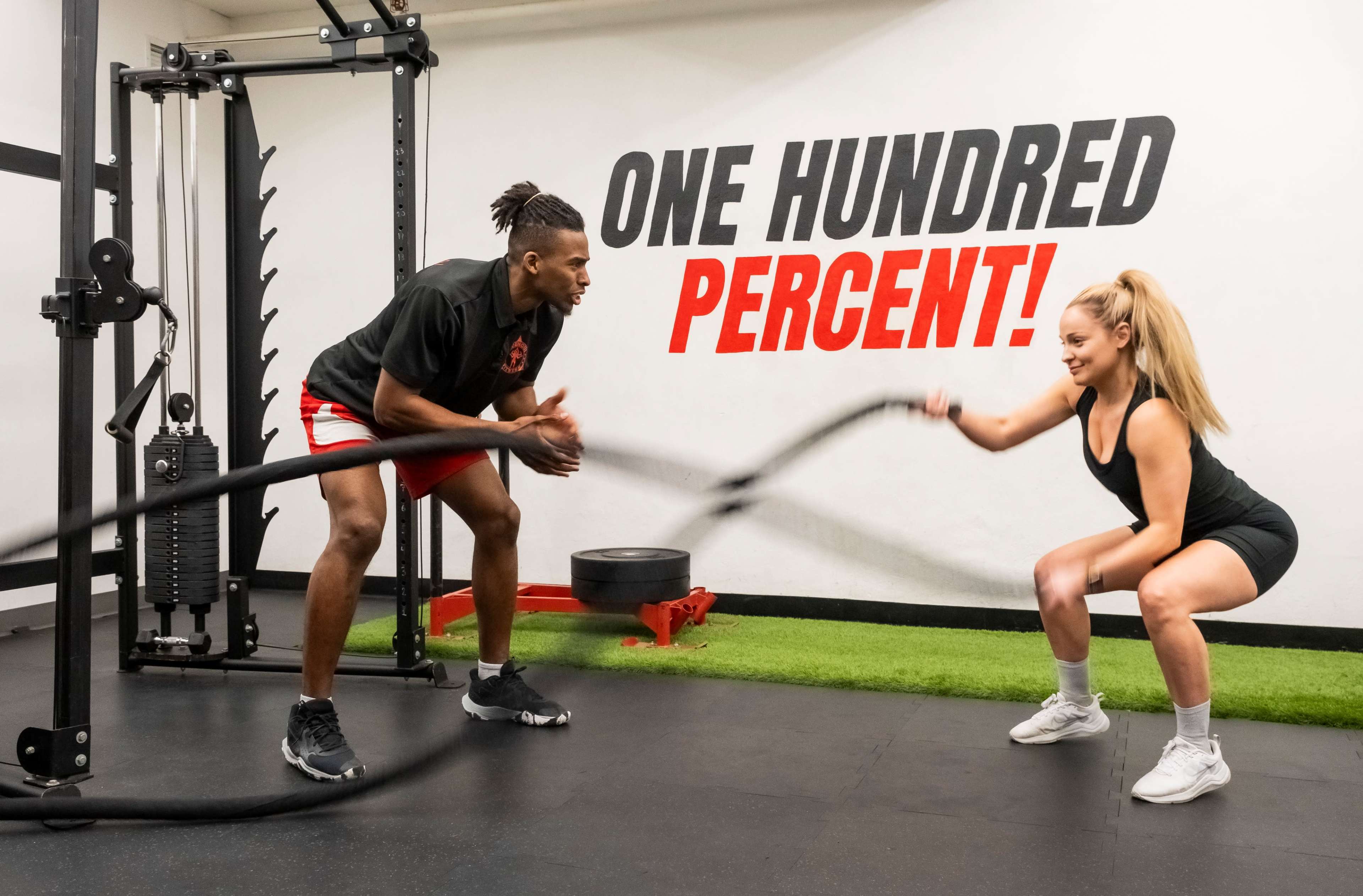 A man and a woman are engaged in a battle ropes workout together in a gym.