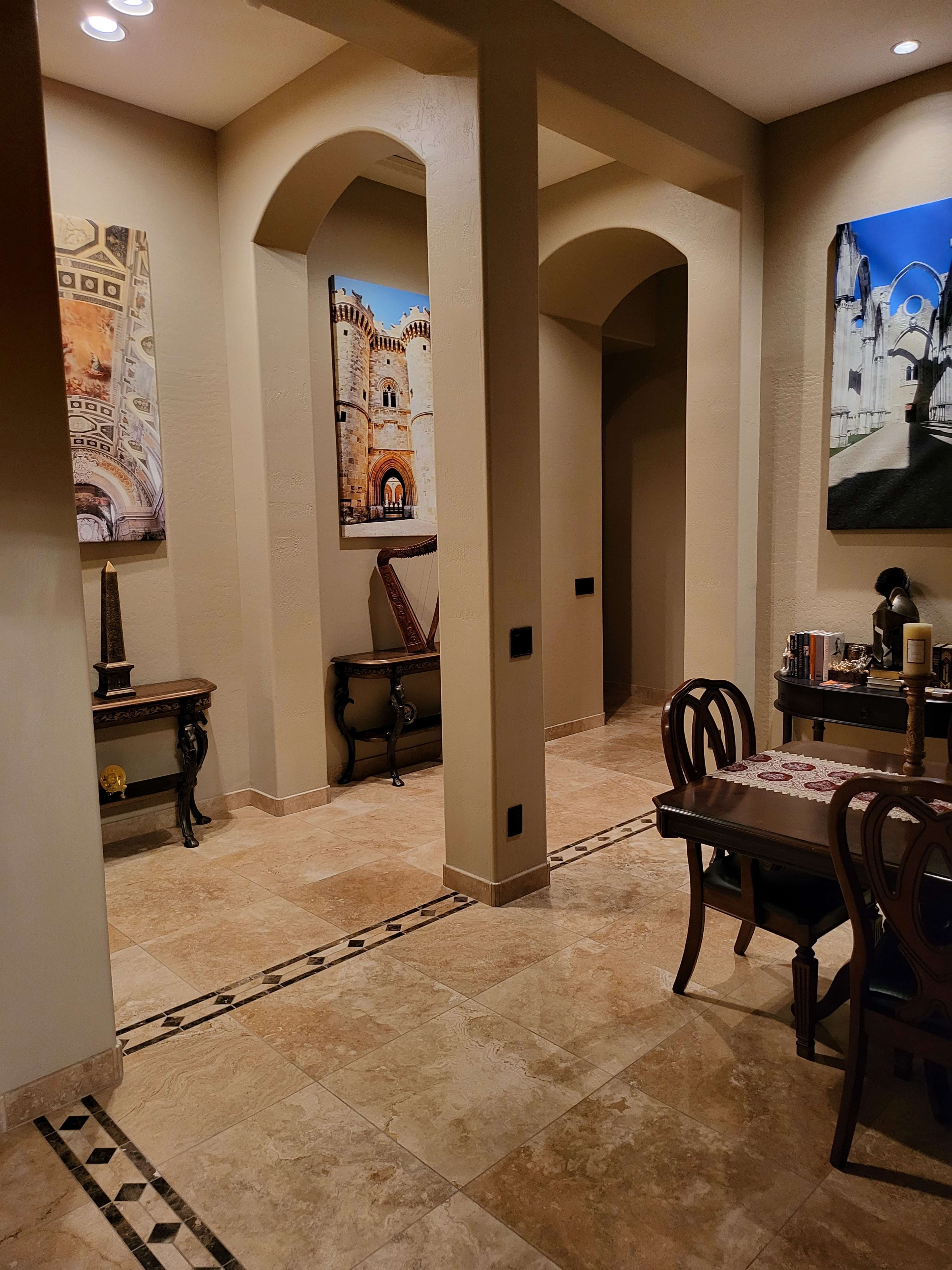 A well-lit corridor with arches leading to distinct wall decorations and tiled flooring in a tastefully designed interior space.