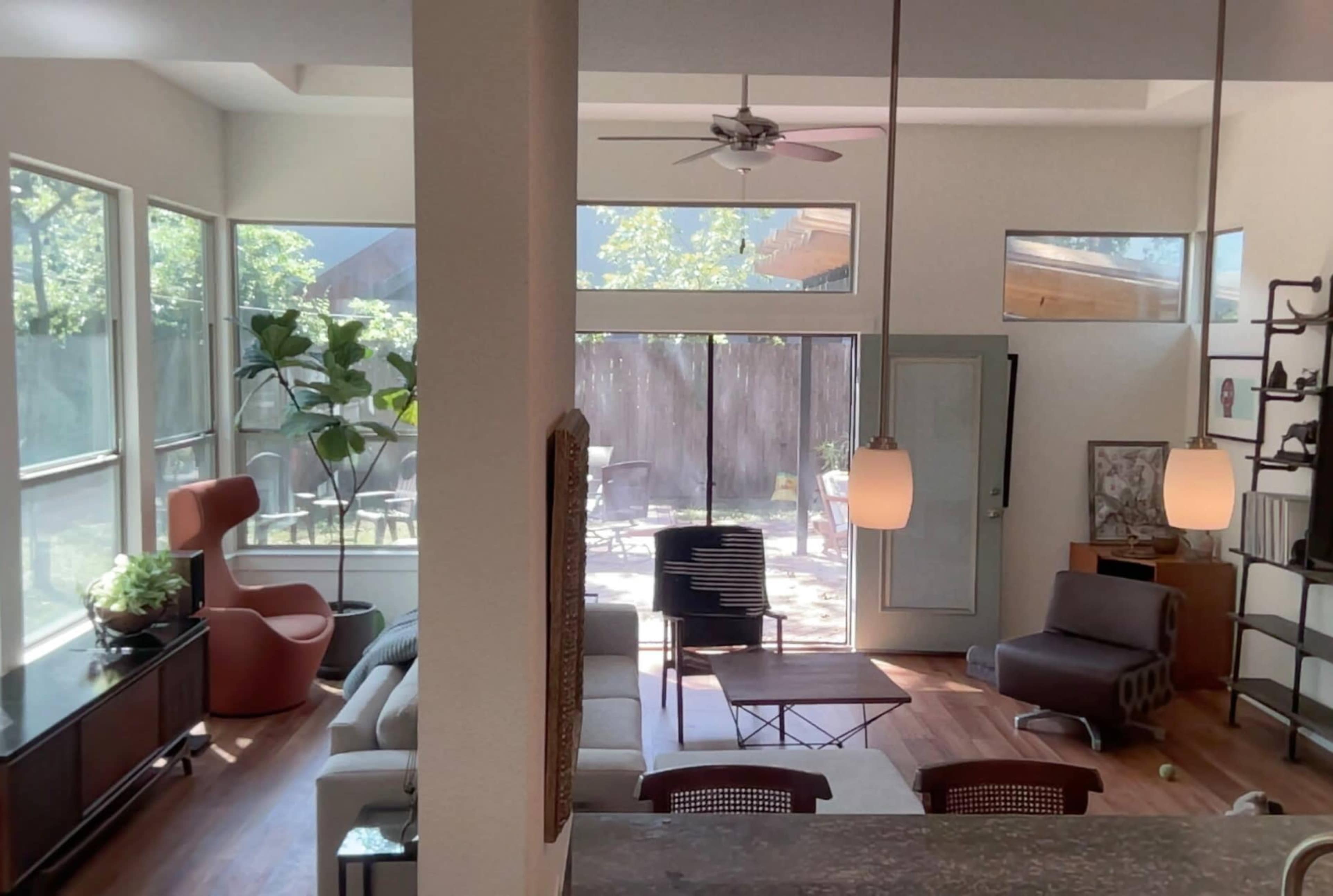 A bright, modern living room with large windows, a mix of seating options, and a view of an outdoor space.