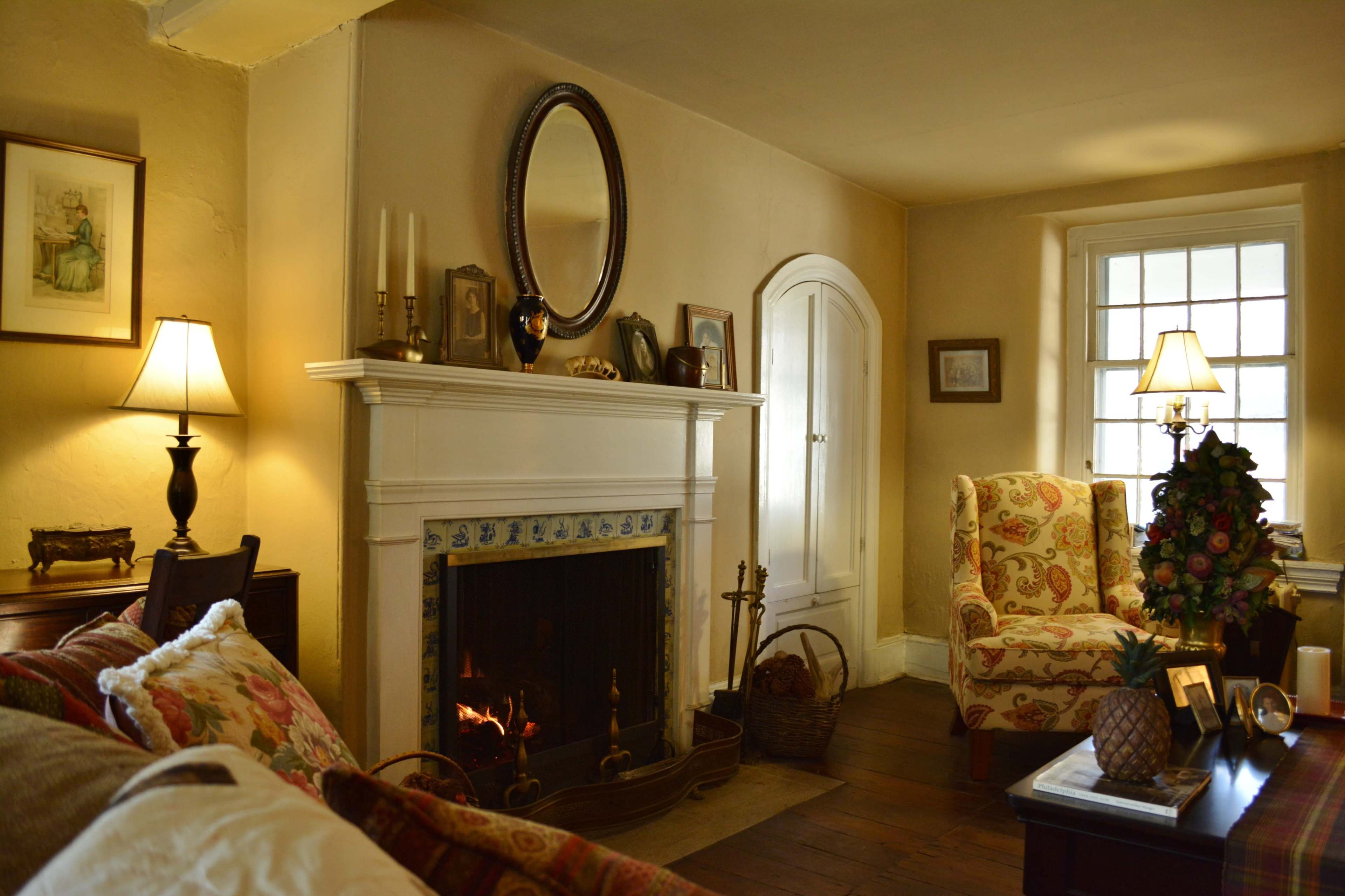A cozy living room featuring a fireplace with a mirror above it, decorative furniture, and warm lighting.