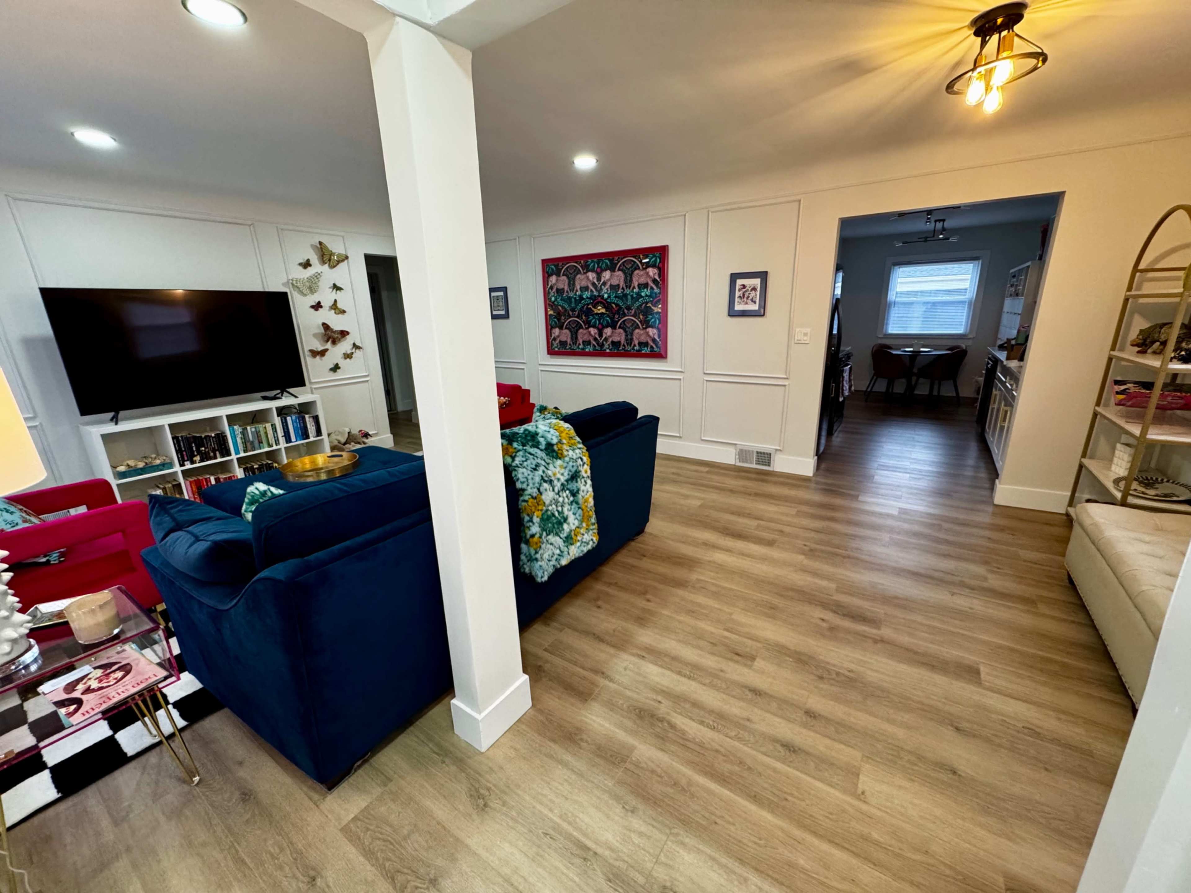 The image shows a living room with a blue couch, a television on the wall, and an open doorway leading to another area of the home.