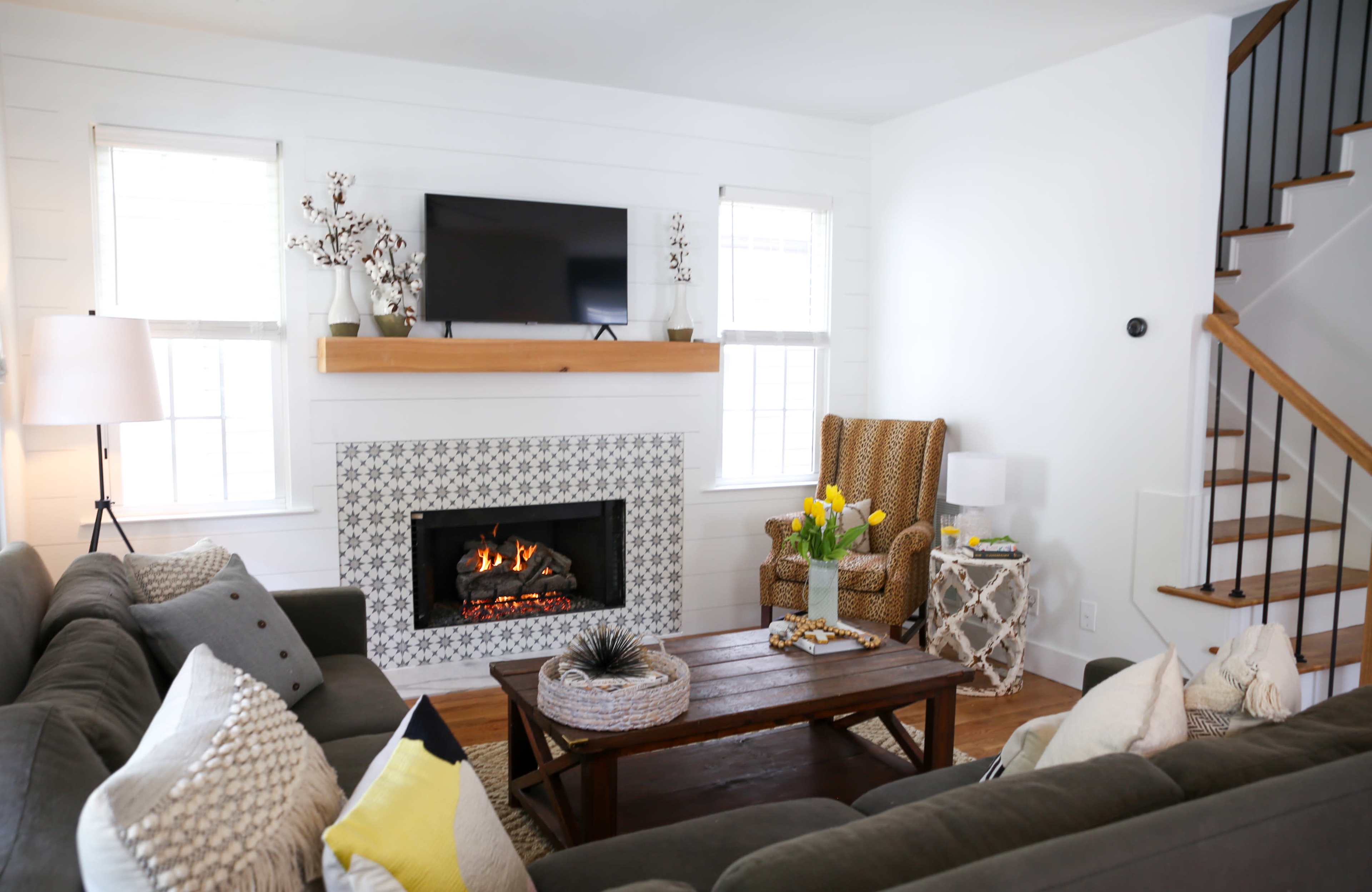 The living room features a fireplace with a flat-screen TV above it, surrounded by decorative elements and comfortable seating.
