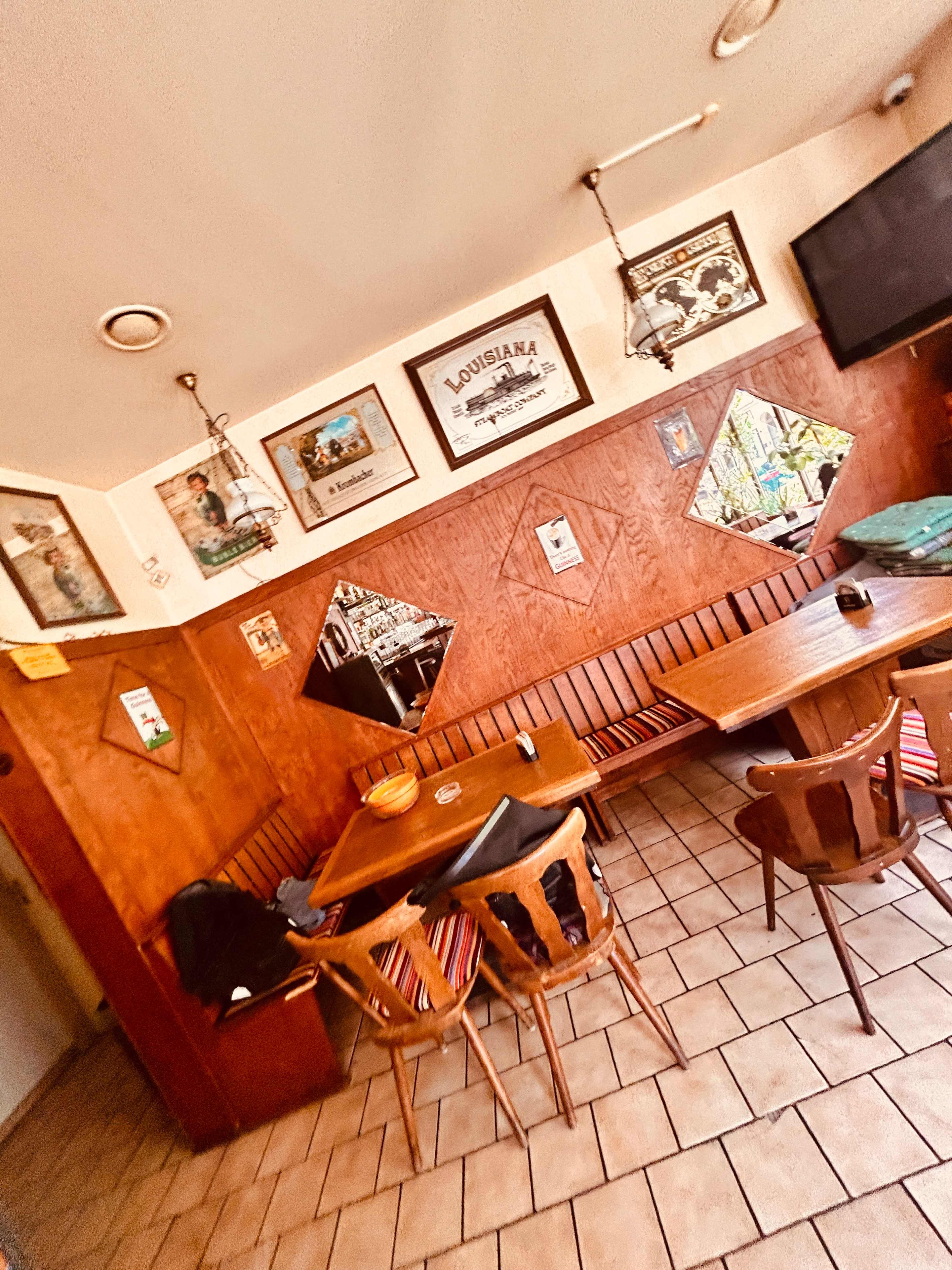 The image shows a cozy restaurant interior with wooden paneling, tables, and framed pictures on the walls.