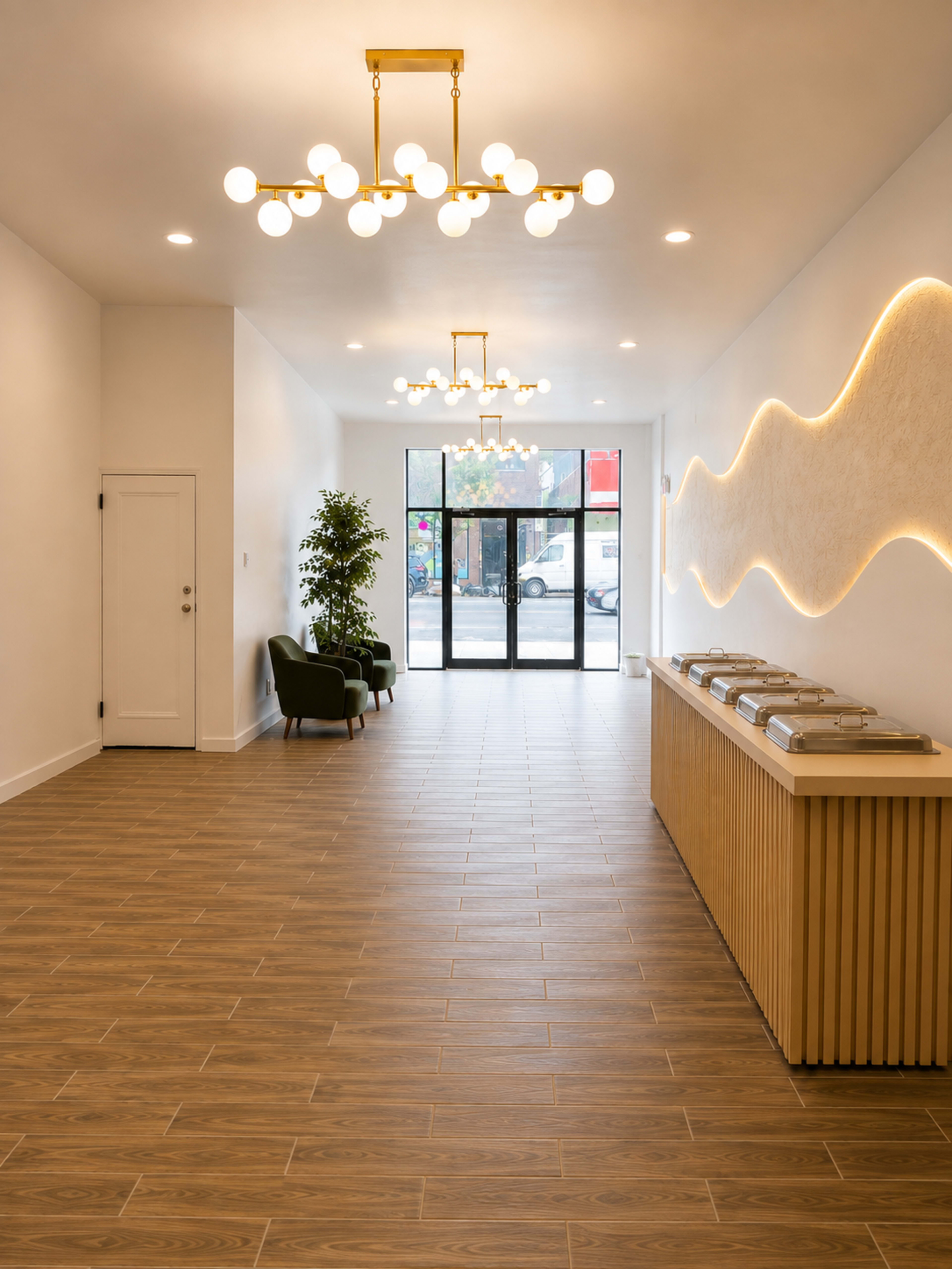 The image shows a modern interior lobby with wood flooring, a reception counter, seating area, and large windows allowing natural light.