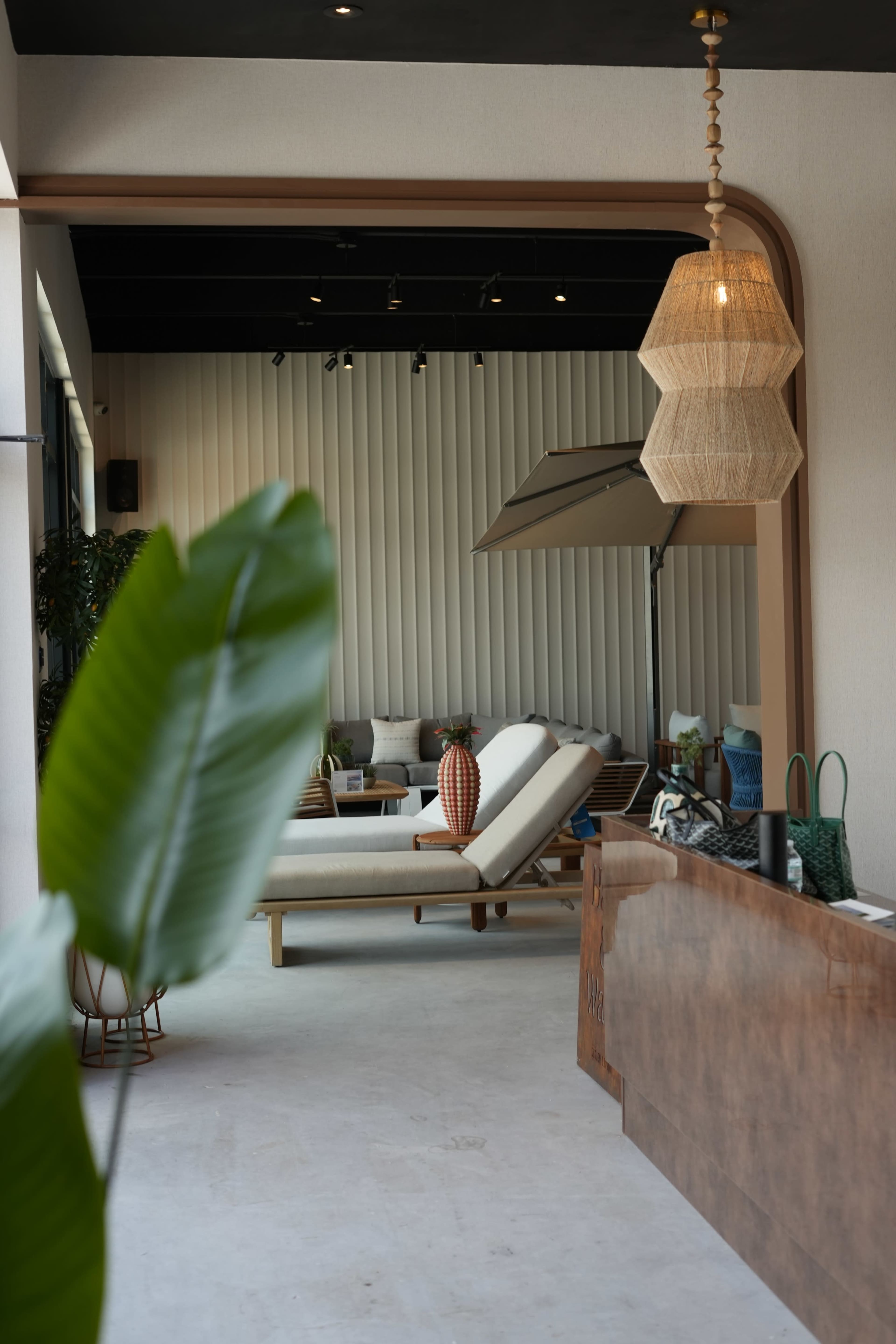 The image shows a modern interior space featuring a reception area with a wooden counter, a sleek lounge area with white seating, and decorative pendant lighting.
