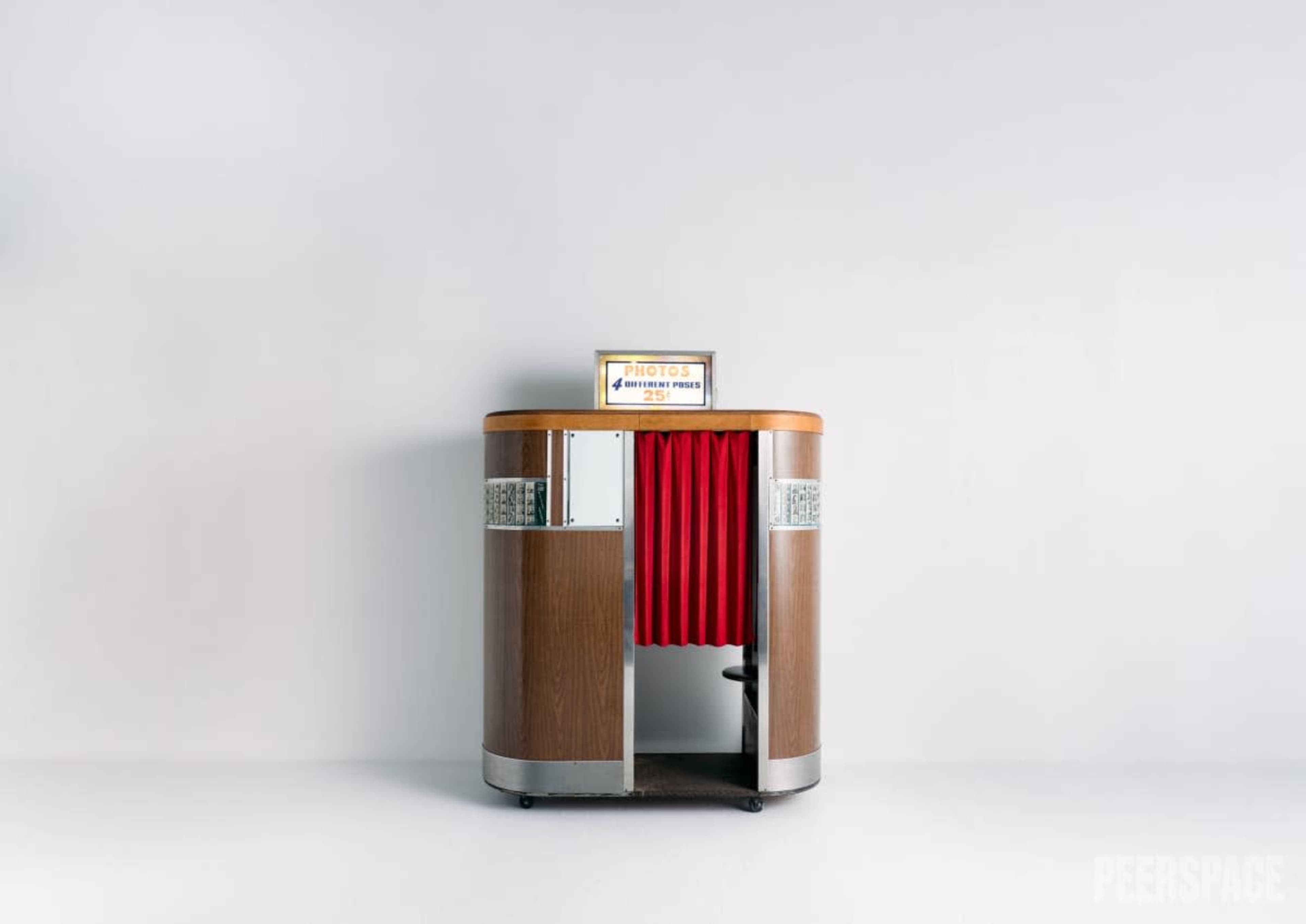The image shows a vintage photo booth with a wooden exterior and red curtains.