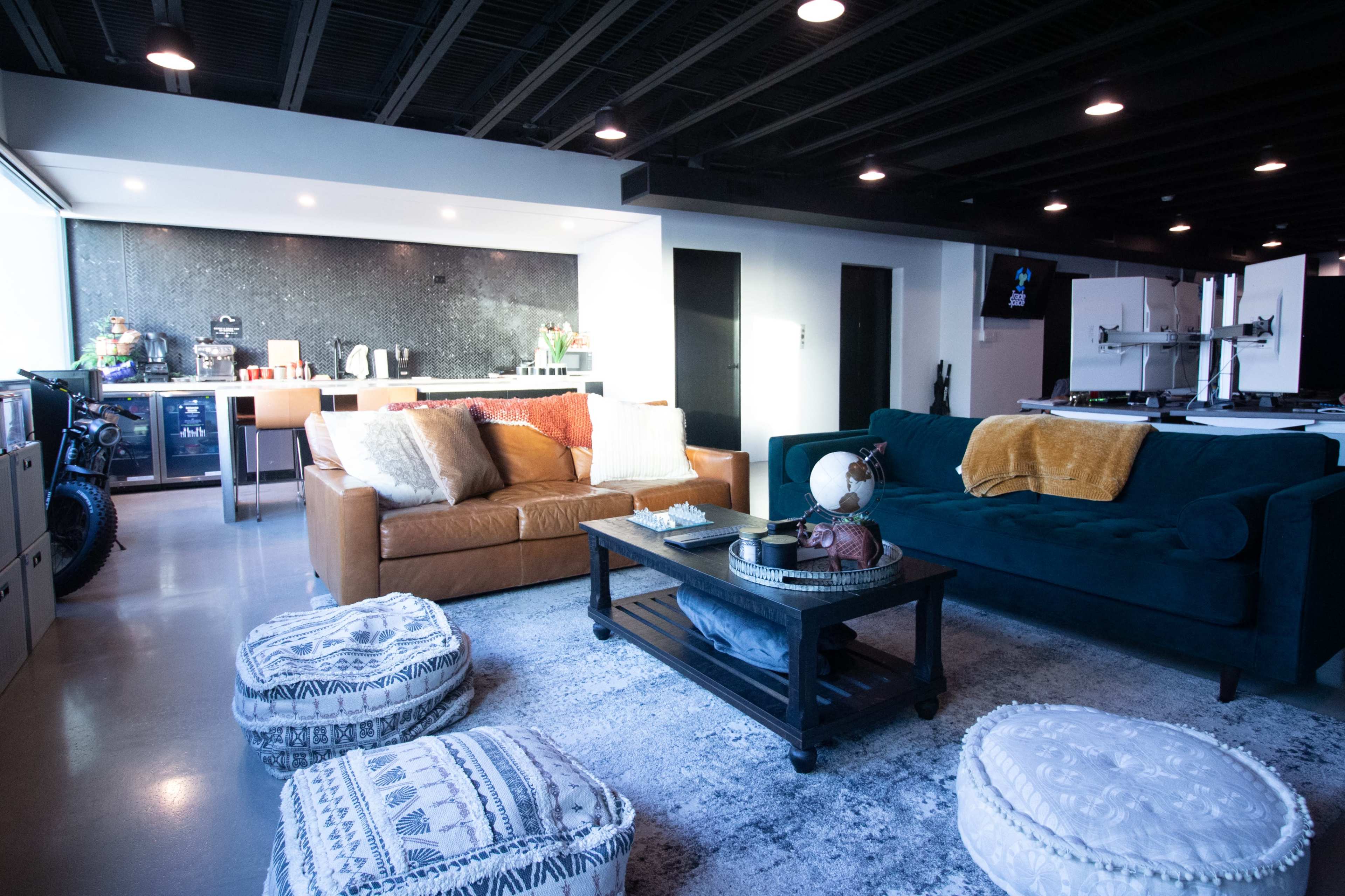 The living area features two sofas, a coffee table, and a kitchen area in the background, all set against a modern interior design.