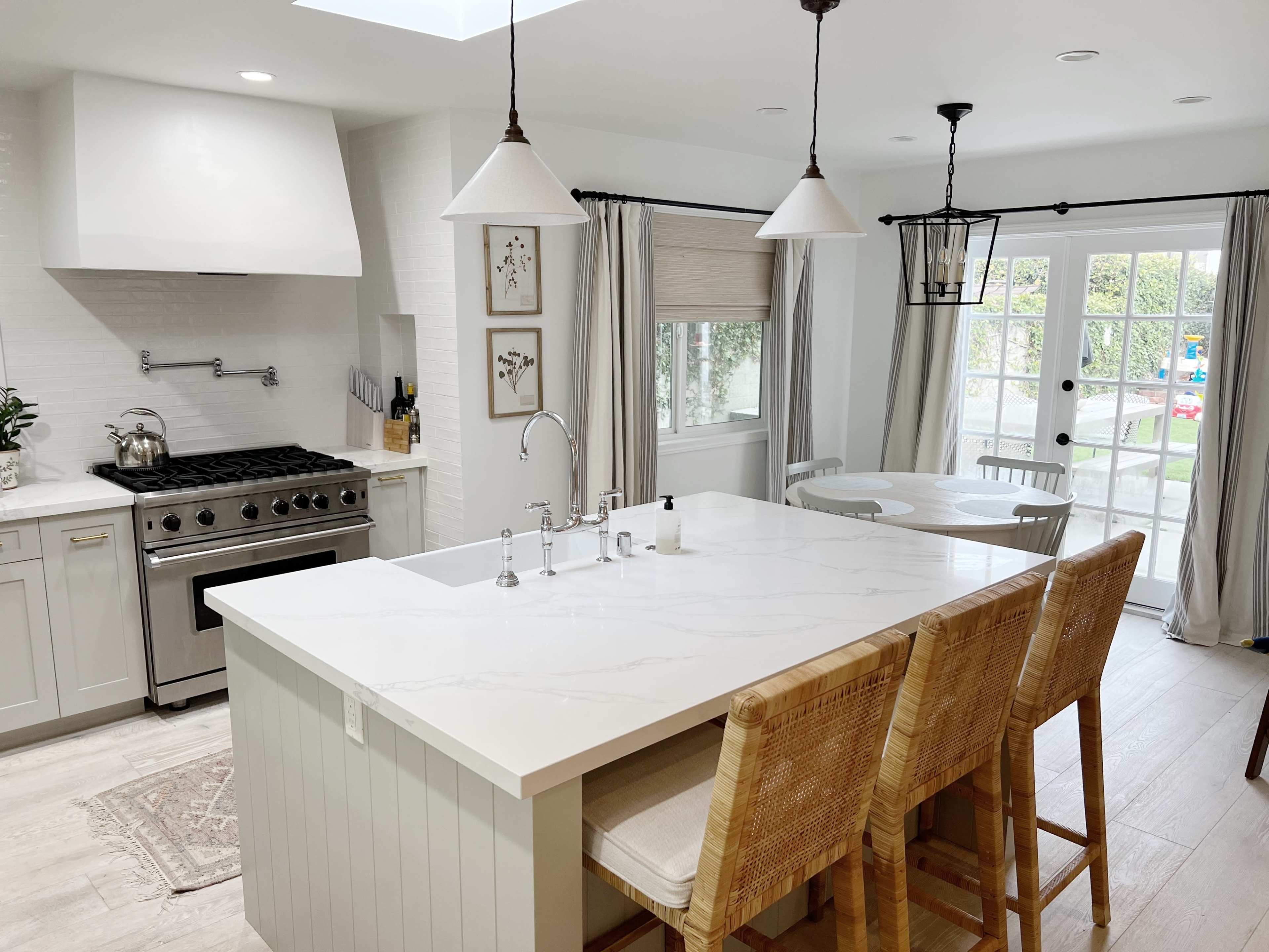 A modern kitchen with a large island, stainless steel appliances, and a dining area that opens to a patio.