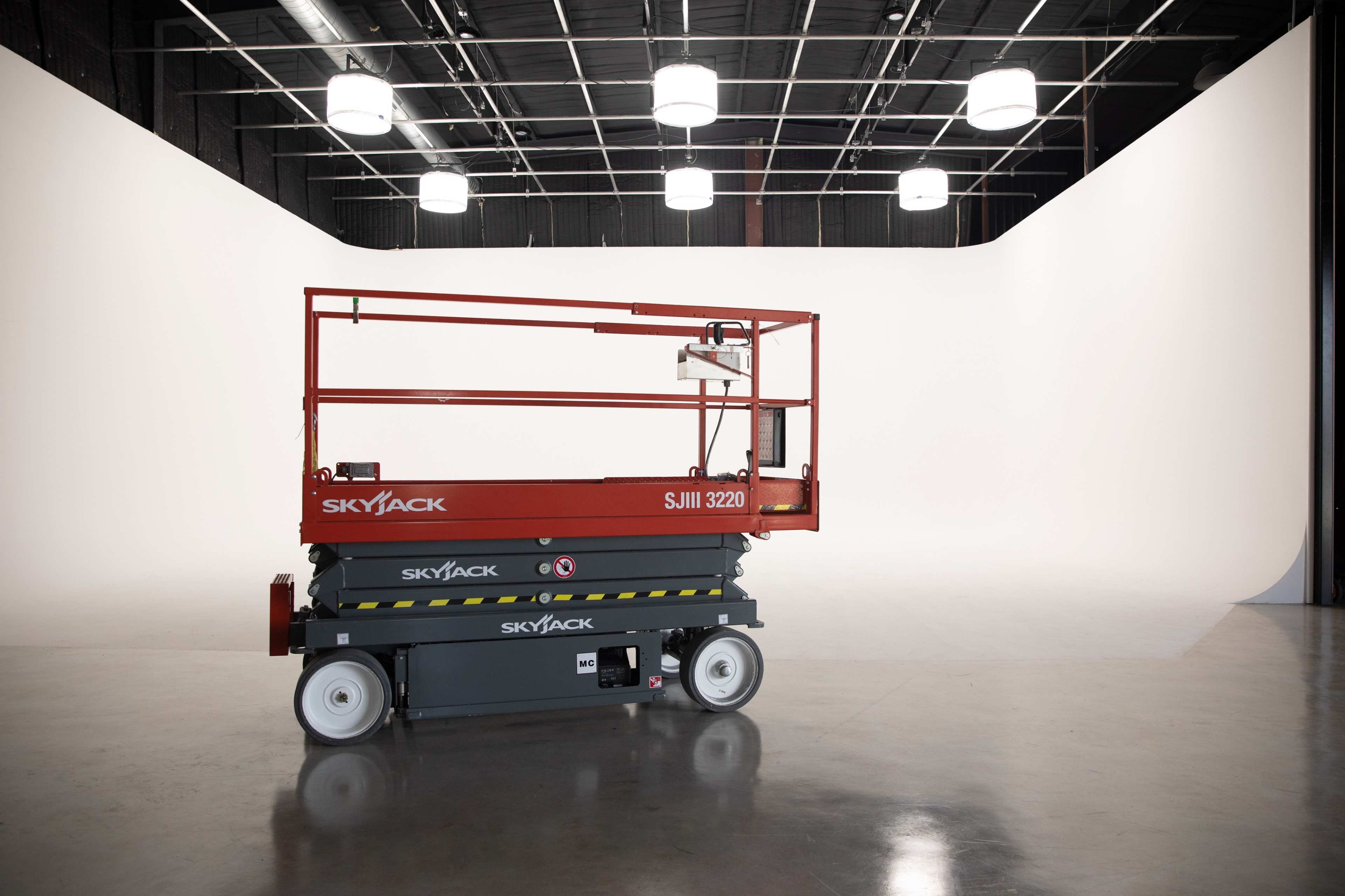 A Skyjack SJIII 3220 aerial work platform is positioned in a spacious, well-lit studio with a white backdrop.