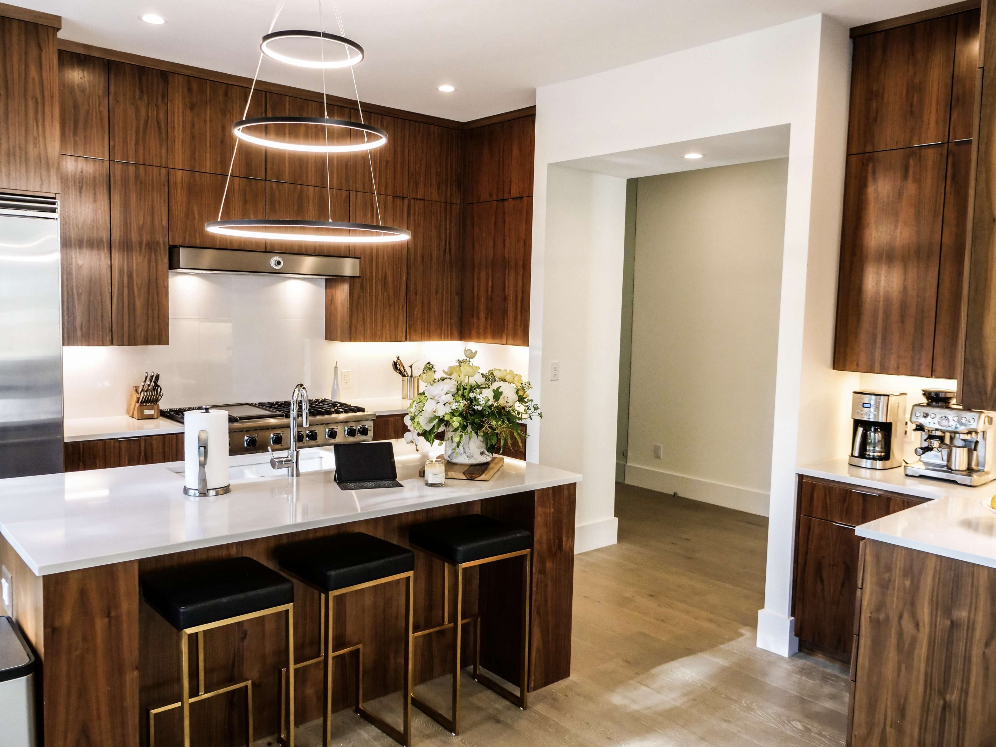 A modern kitchen with wooden cabinetry, a central island with bar stools, and stainless steel appliances.