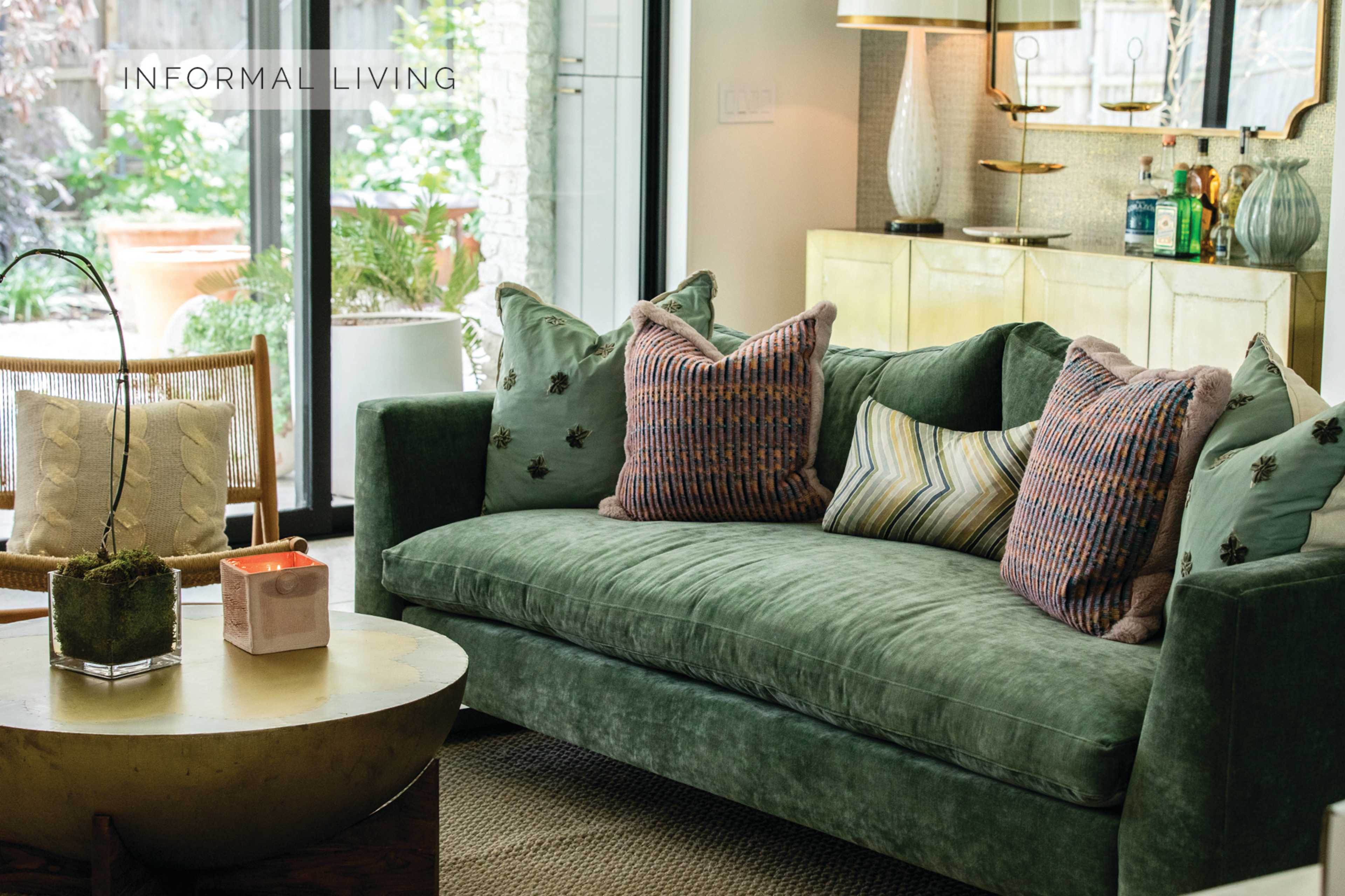 A green upholstered sofa with patterned pillows, accompanied by a wooden coffee table and a decorative plant in a modern living space.
