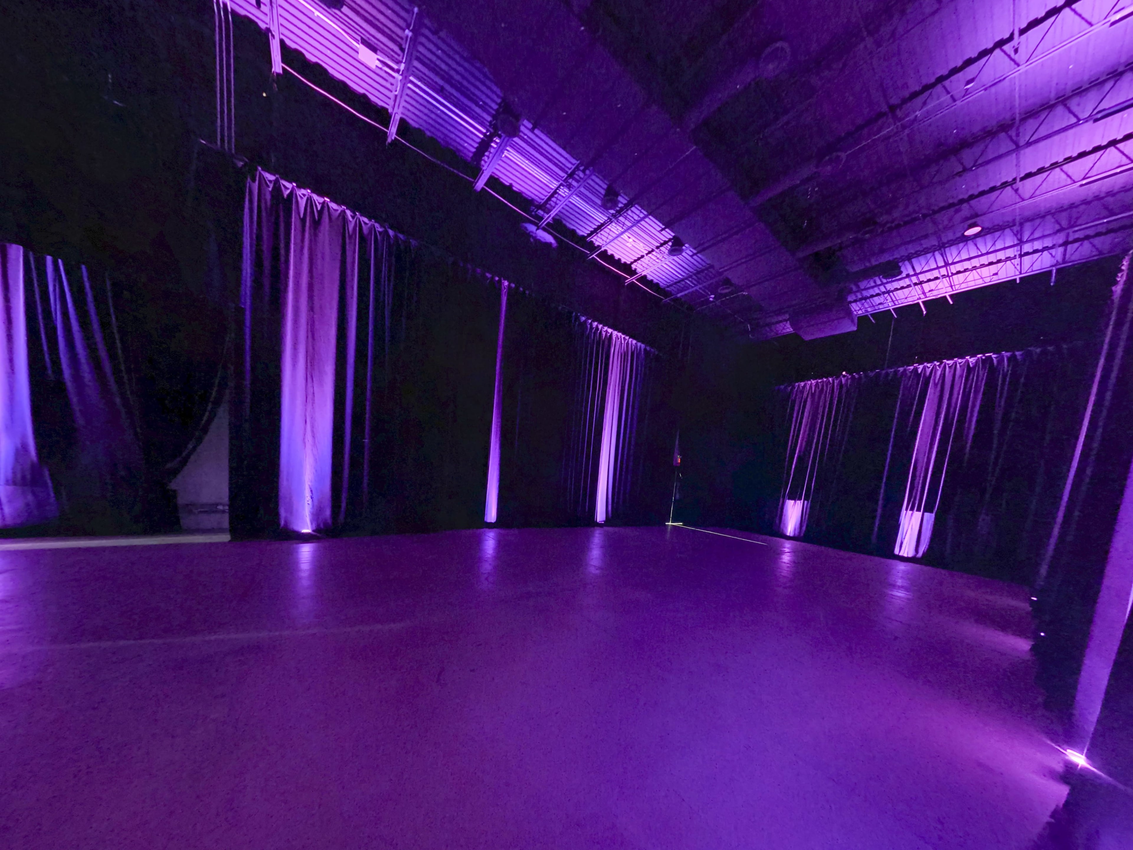 A dimly lit performance space with purple curtains and lighting.