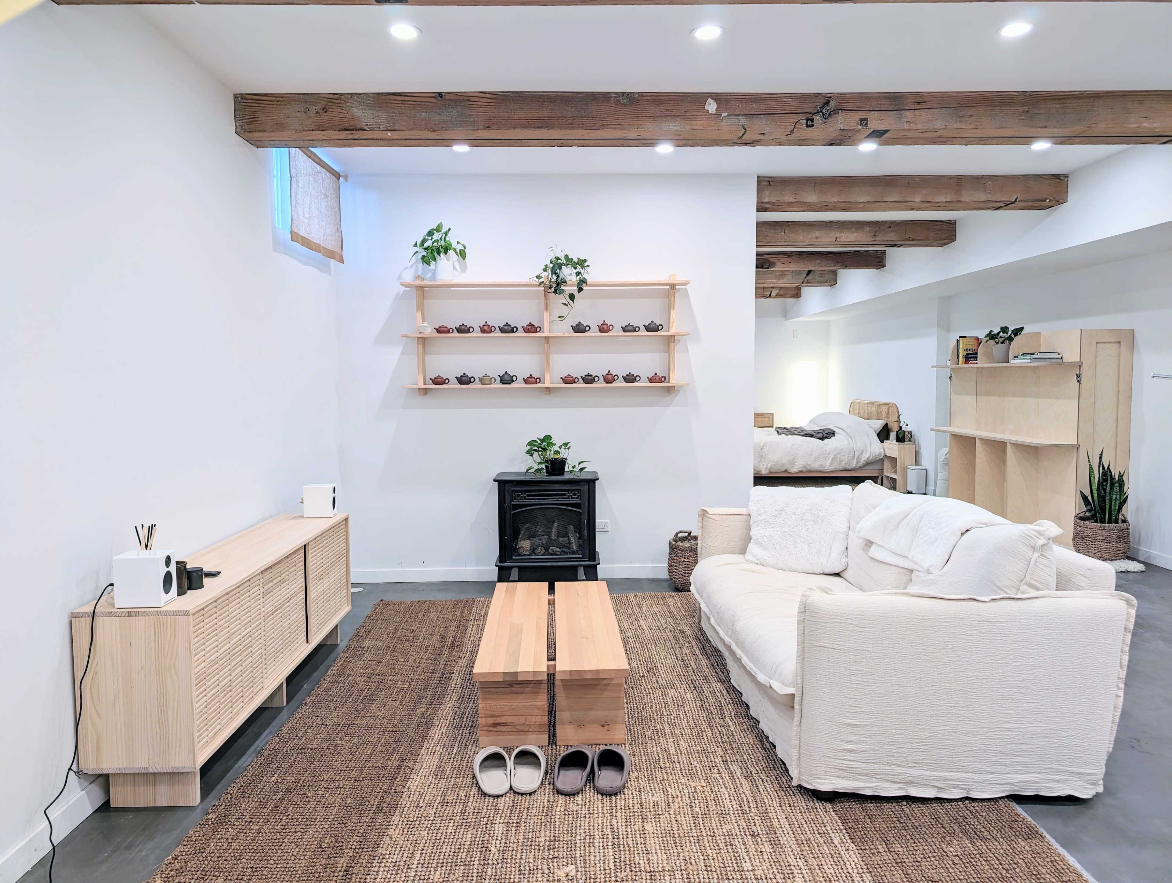 A minimalist living room with a white sofa, a wooden coffee table, and shelves displaying potted plants.
