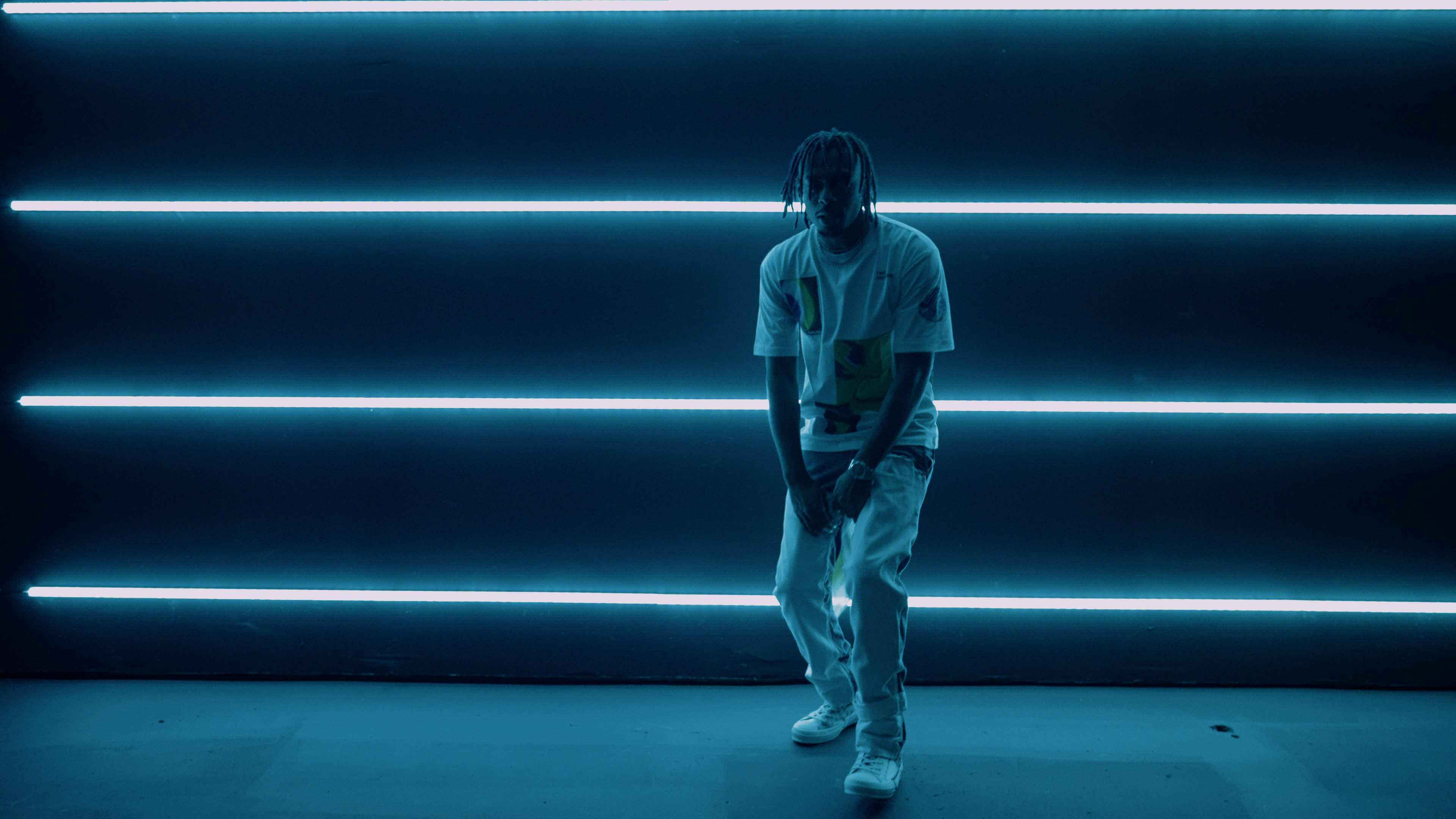 A person stands in front of a wall illuminated by horizontal neon blue lights.