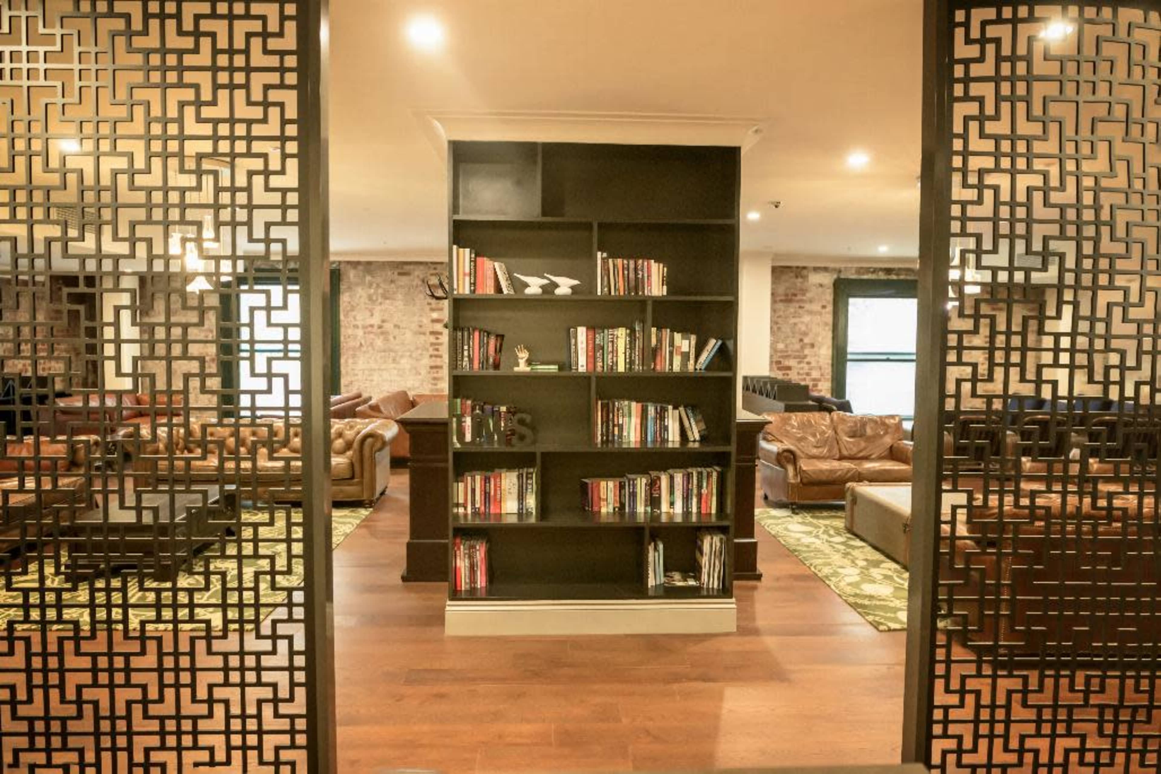 A modern reading area with a central bookshelf surrounded by leather couches and a decorative pattern on the partition.