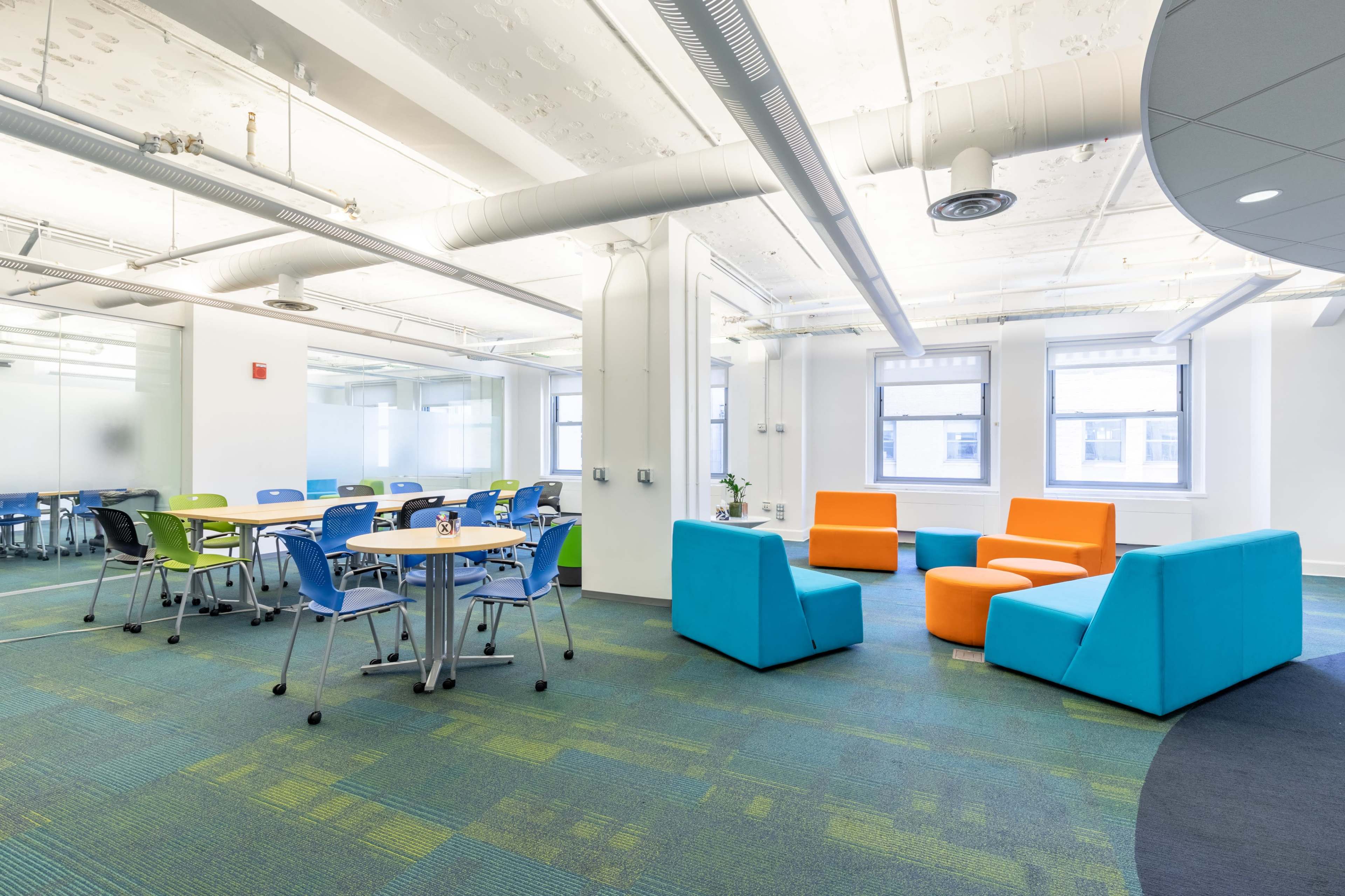 A modern office space with colorful seating areas and tables arranged for meetings.