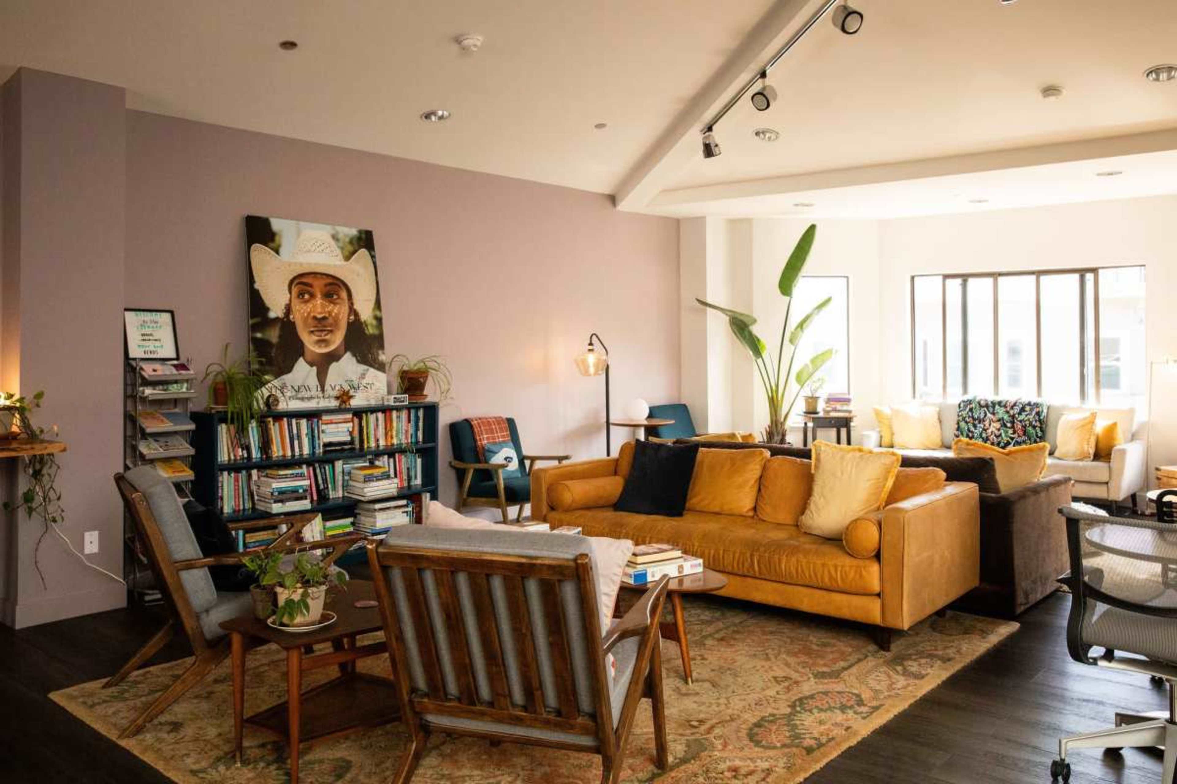 The image shows a cozy living room with a yellow leather sofa, a bookshelf filled with books, and various plants, all under soft lighting and featuring a portrait on the wall.