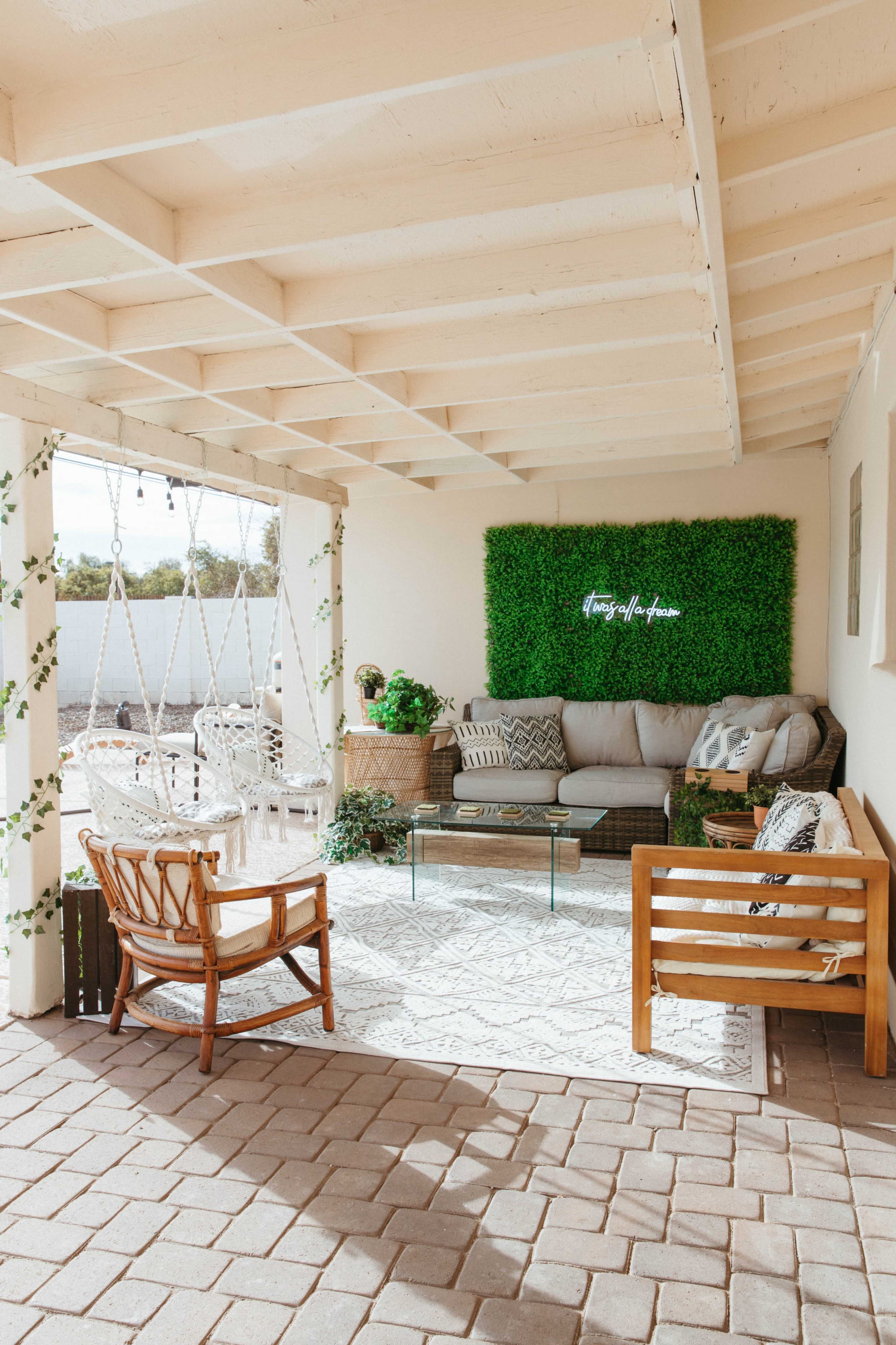 A cozy outdoor seating area with a green wall, comfortable furniture, and decorative plants.