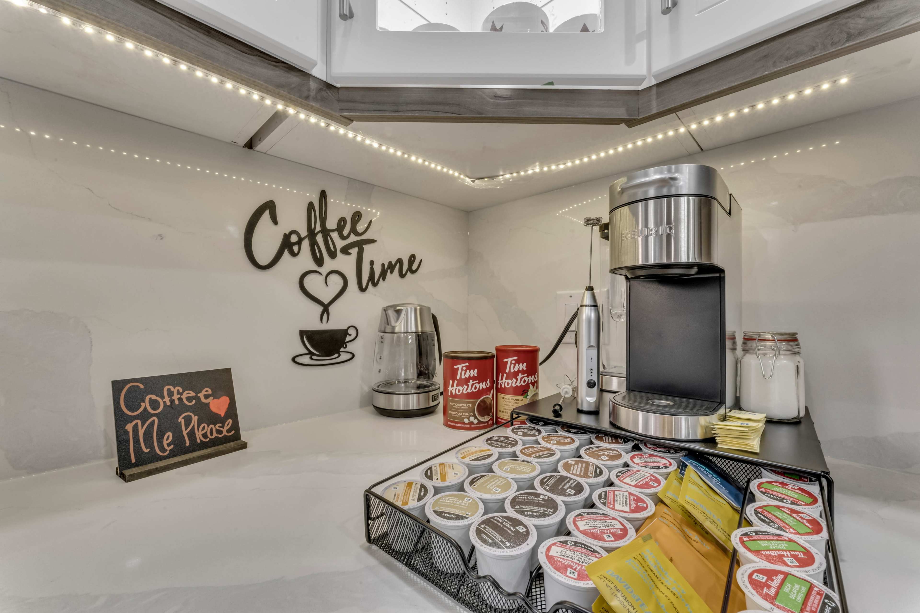 A coffee station with a coffee maker, various coffee pods in a basket, and a decorative sign that reads "Coffee Time."