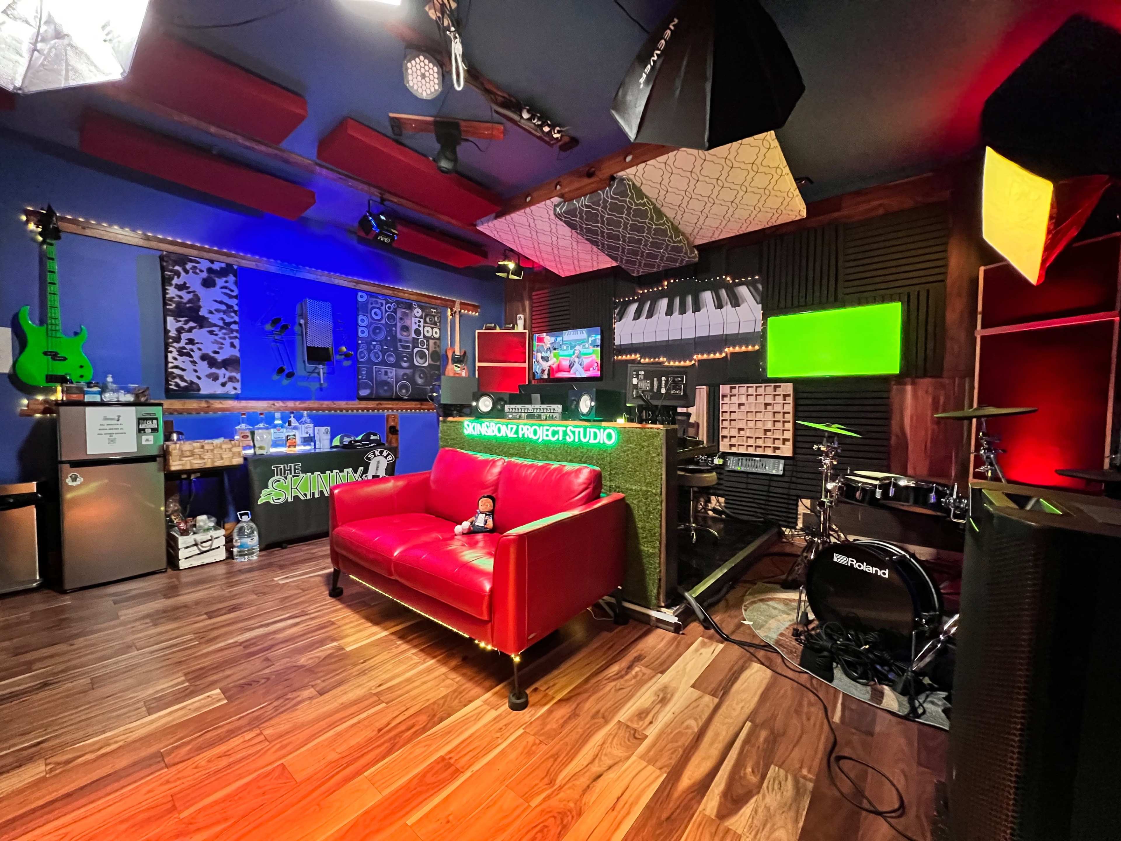 A vibrant music studio with a red sofa, various musical instruments, colorful decor, and soundproofed walls.
