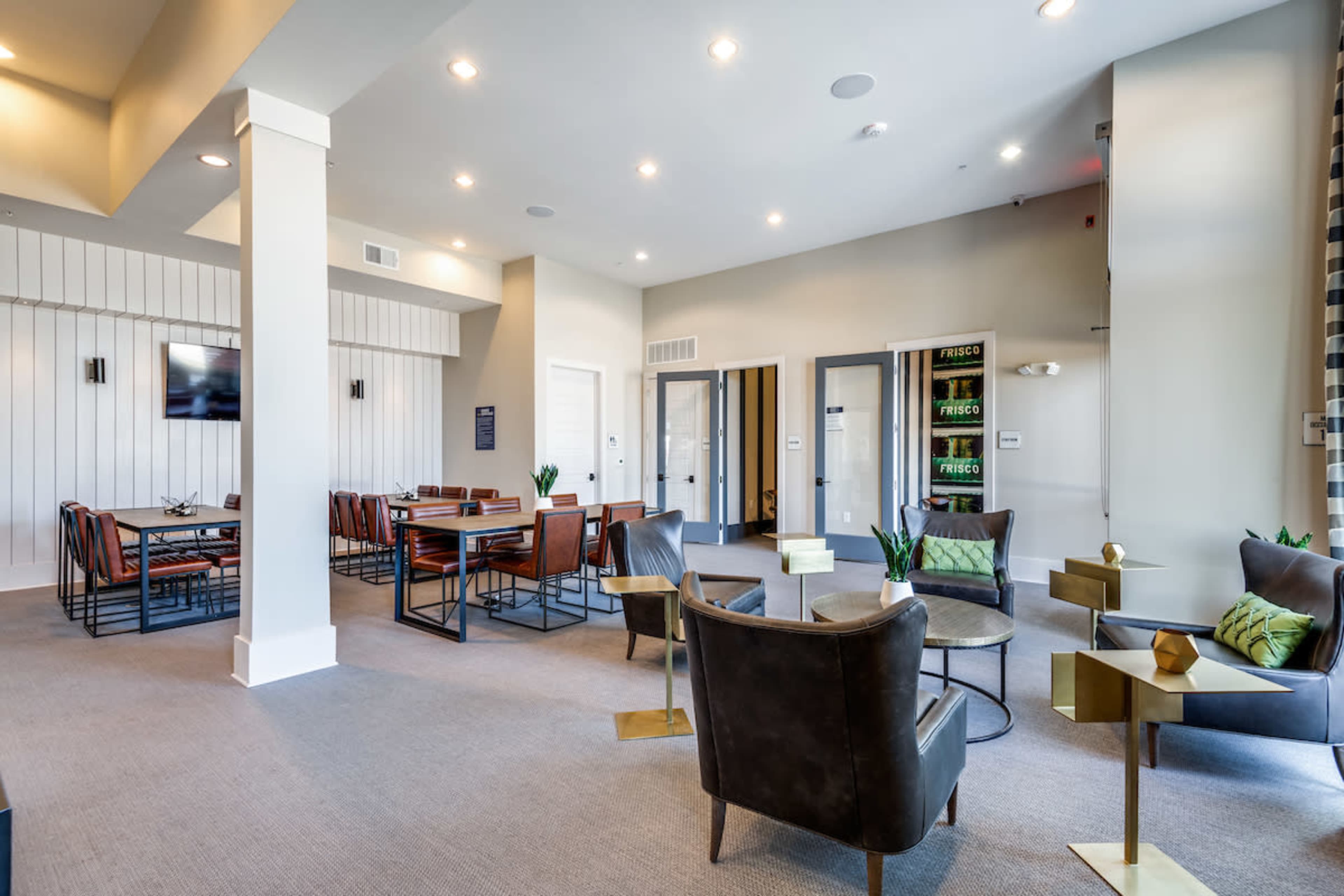A modern common area with seating, a dining table, and doors leading to other rooms.