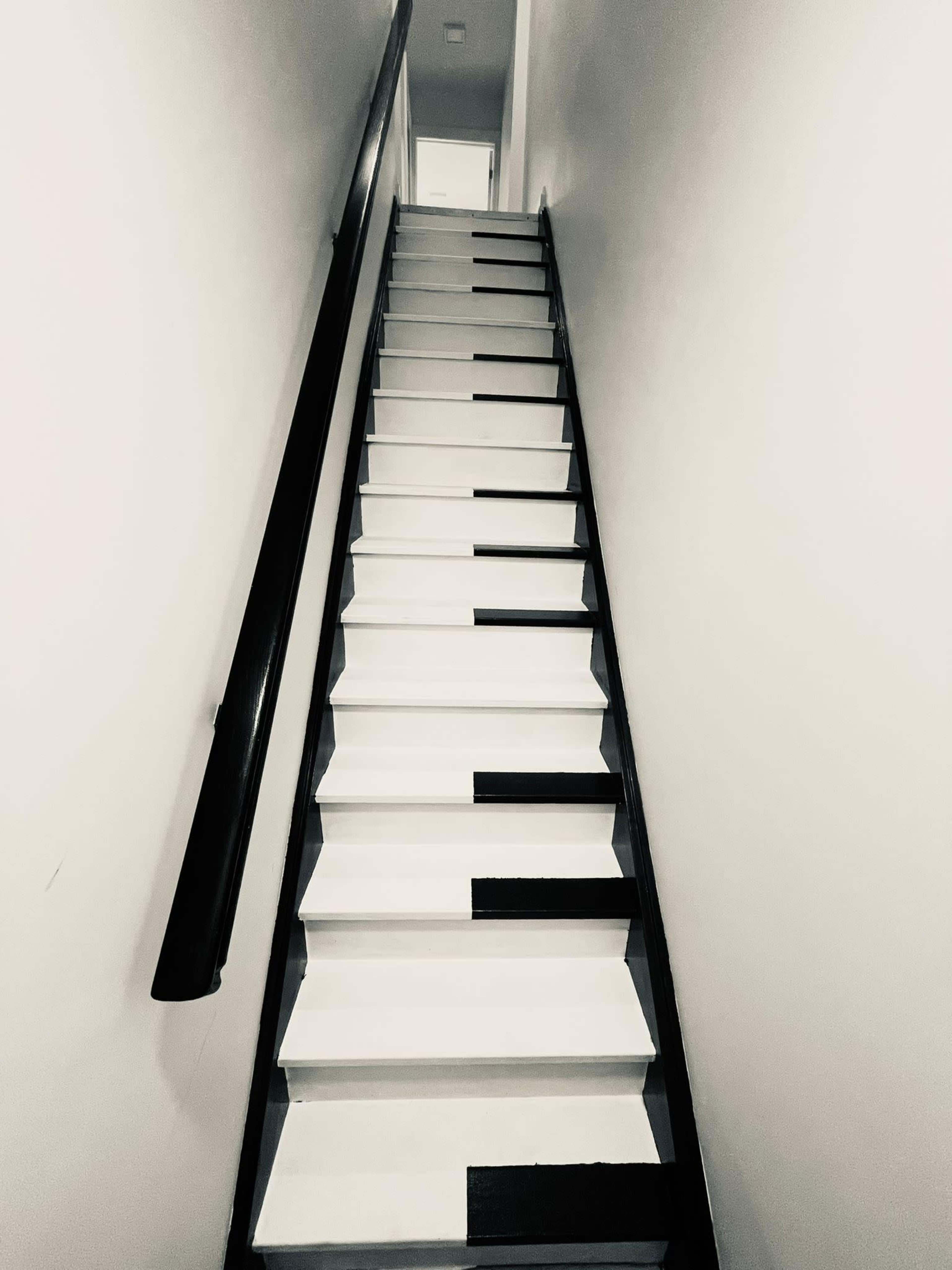 A staircase with steps painted to resemble a piano keyboard ascends into a well-lit hallway.
