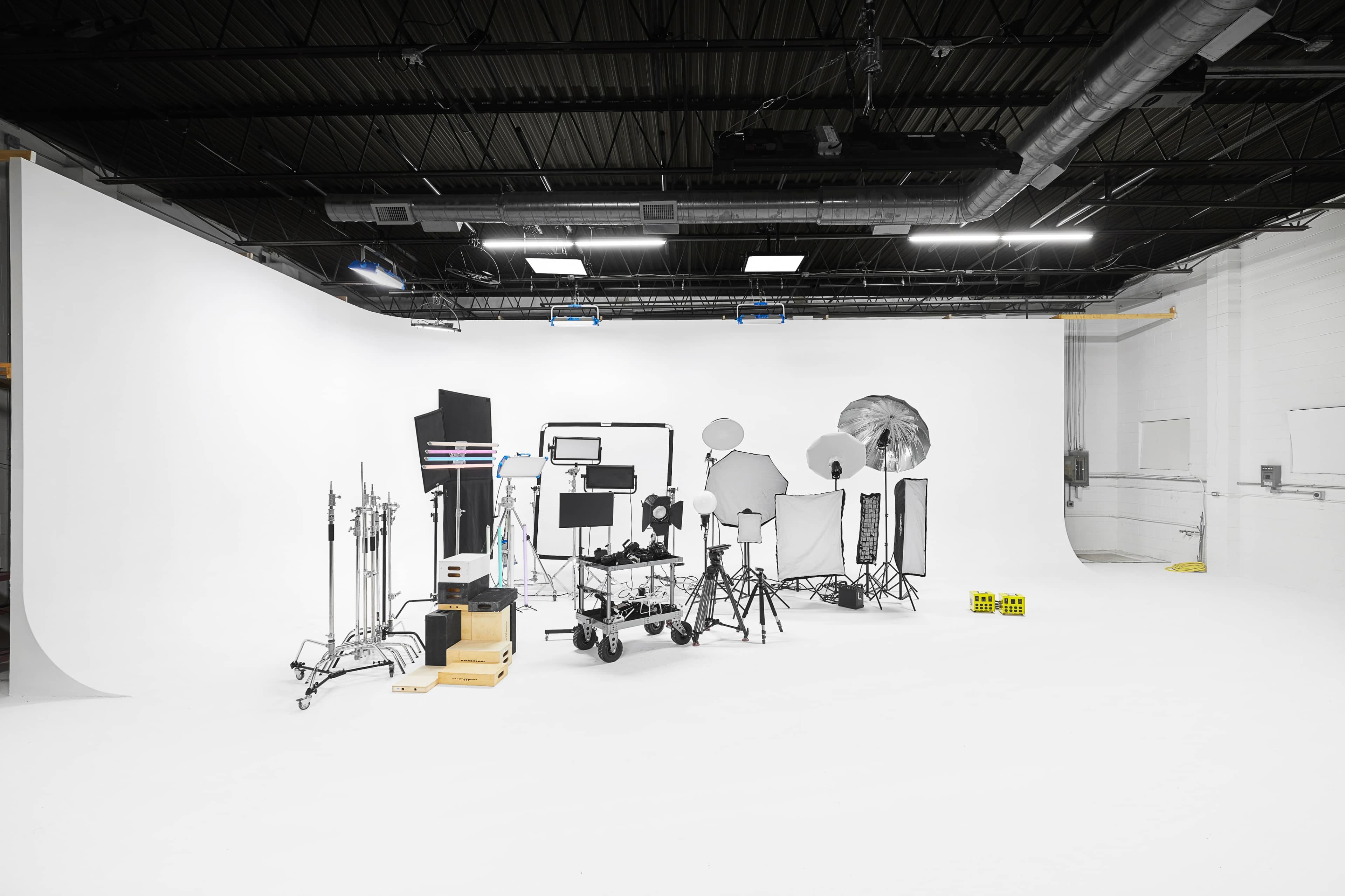 A photography studio is set up with various lighting equipment, backdrops, and stands arranged on a white floor.