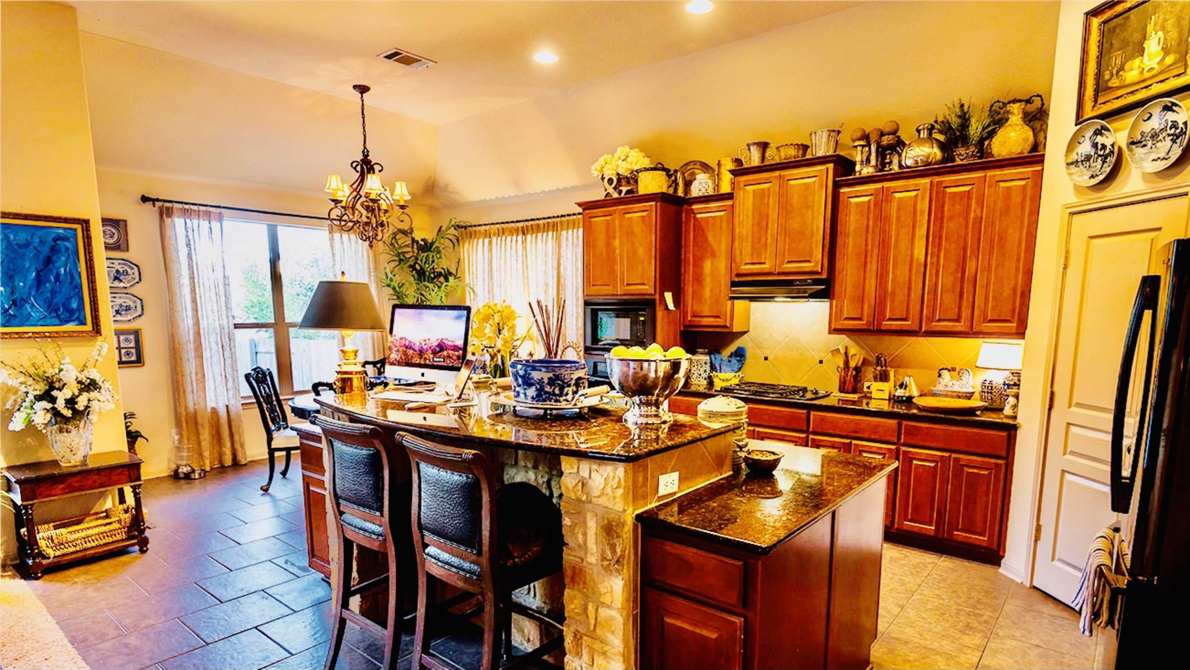 A well-organized kitchen featuring wooden cabinets, a granite countertop, and a dining area with bar stools.