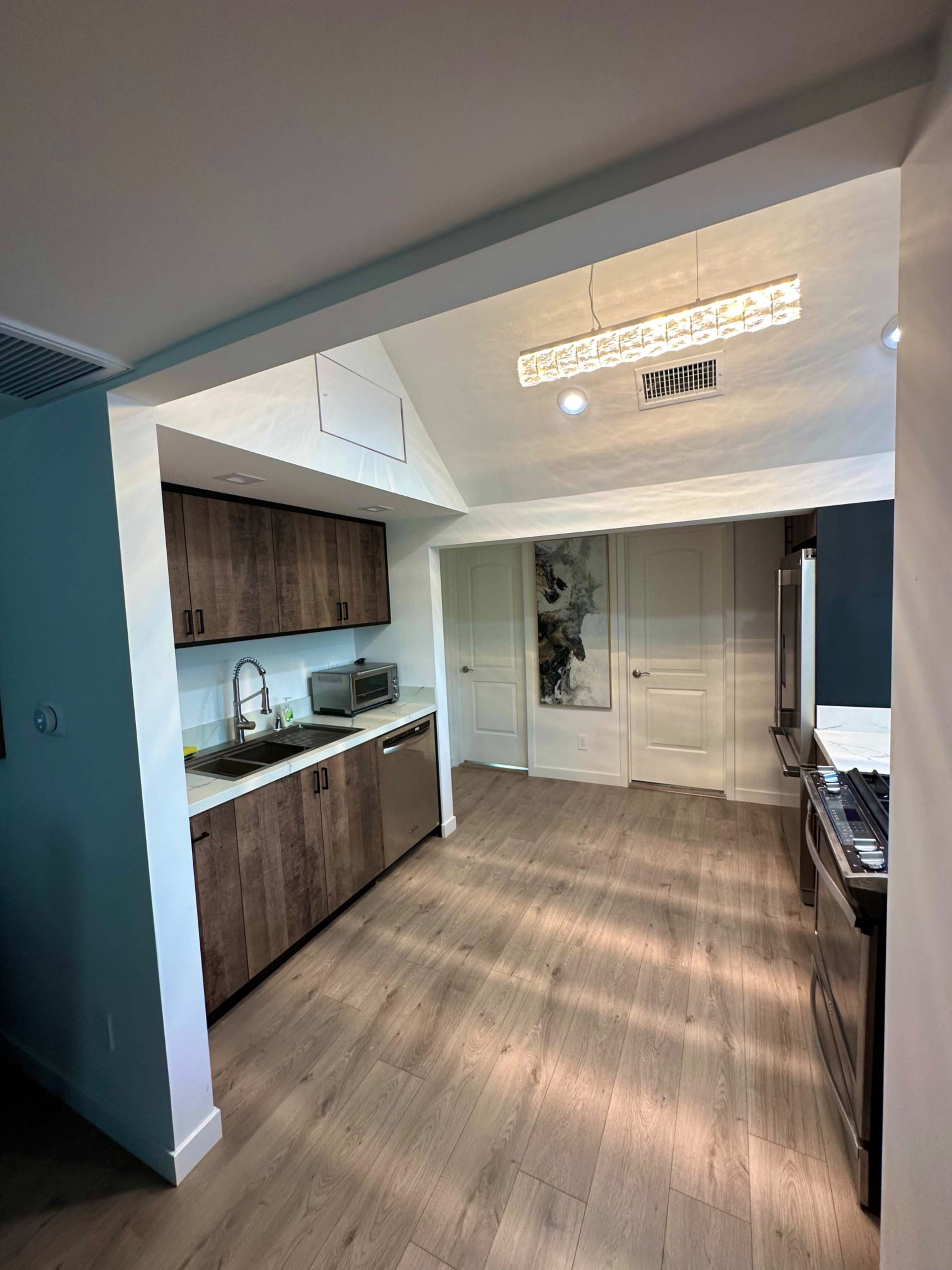 A modern kitchen features wooden cabinets, stainless steel appliances, and a spacious layout with a skylight.