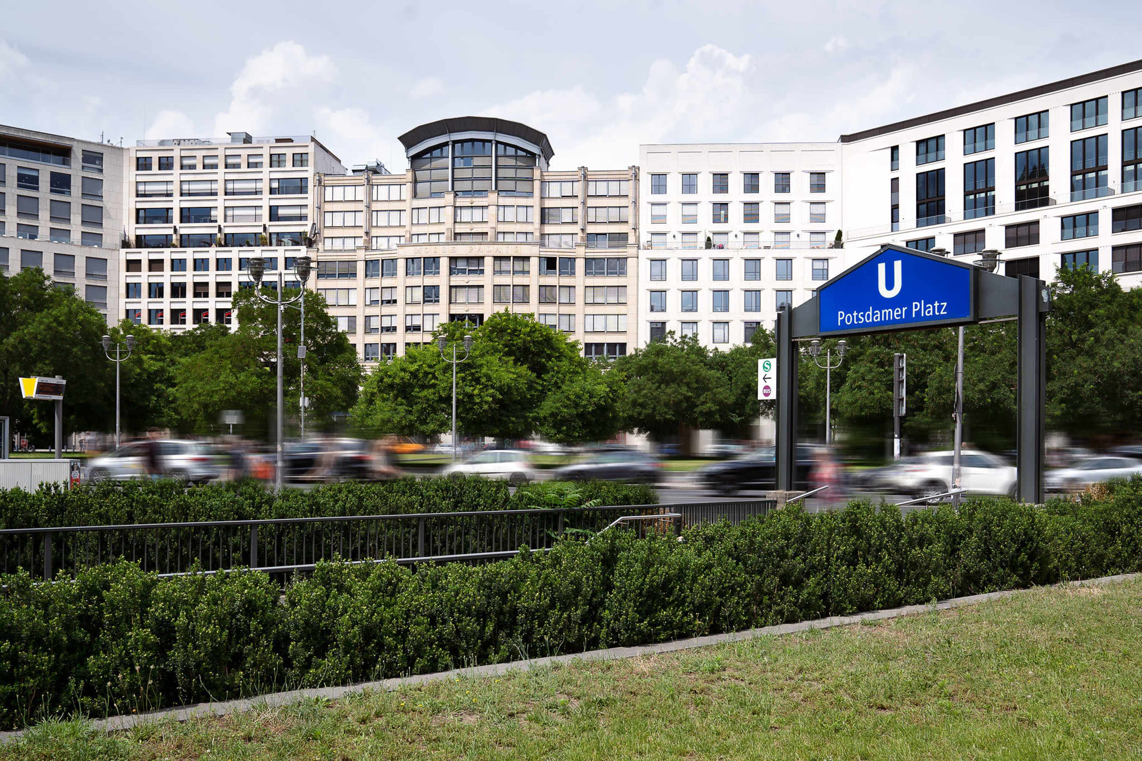 The image shows the U-Bahn station sign at Potsdamer Platz, with modern buildings and traffic in the background.