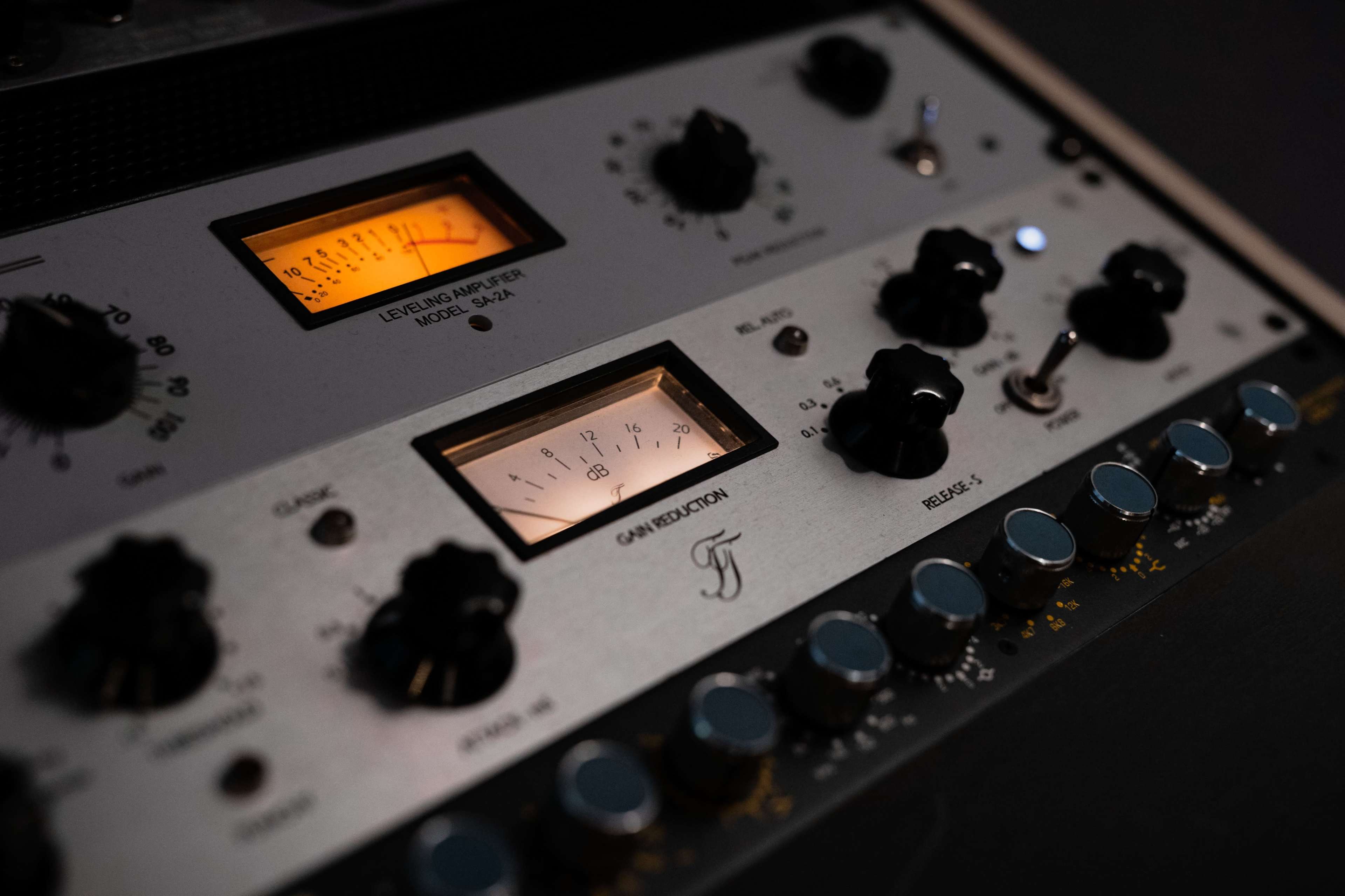 A close-up of audio equipment with illuminated meter displays and various knobs for adjustment.