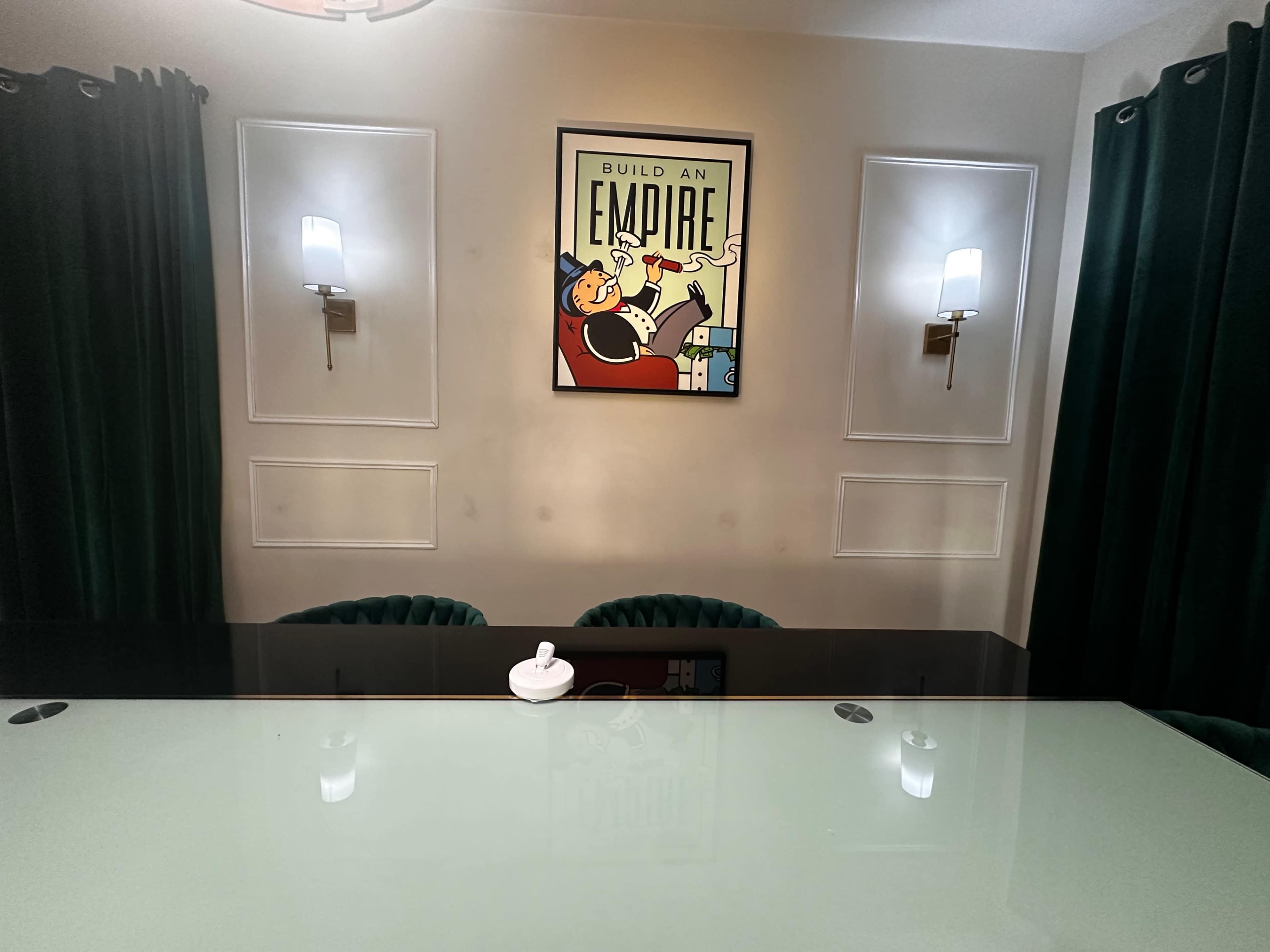 The image shows a room with a glass table and green curtains, featuring a framed poster that says "BUILD AN EMPIRE" on the wall.
