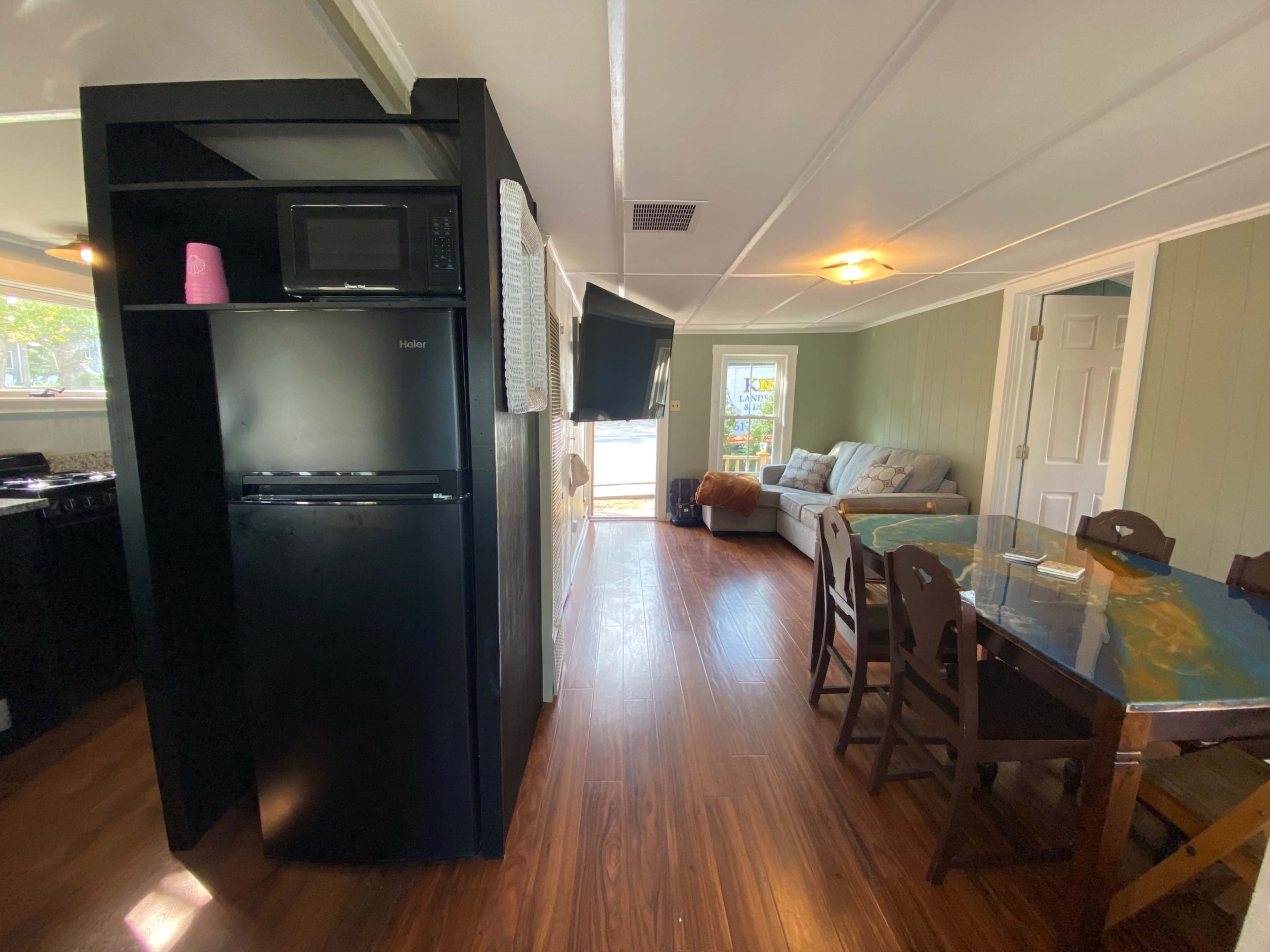 A cozy living space with a kitchenette on the left, a dining table, and a seating area with a sofa.