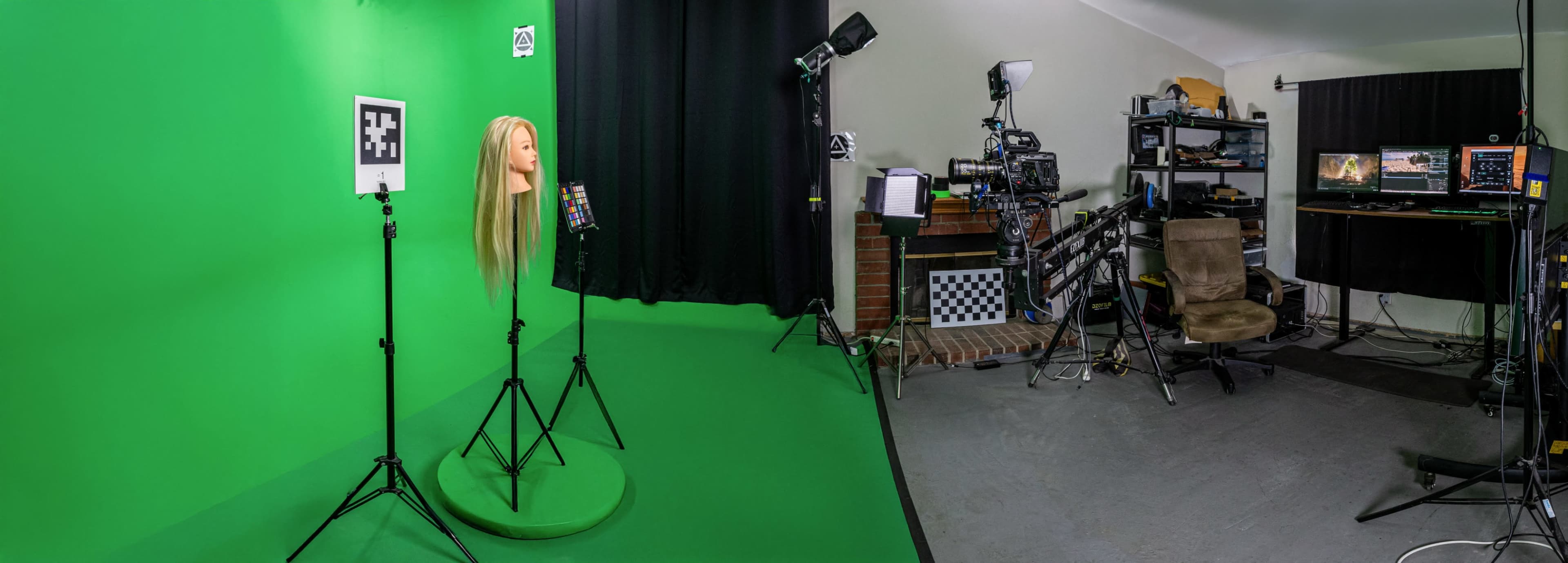 The image shows a studio setup with a green screen, a mannequin head with long hair, camera equipment, and a workspace area with monitors and computers.