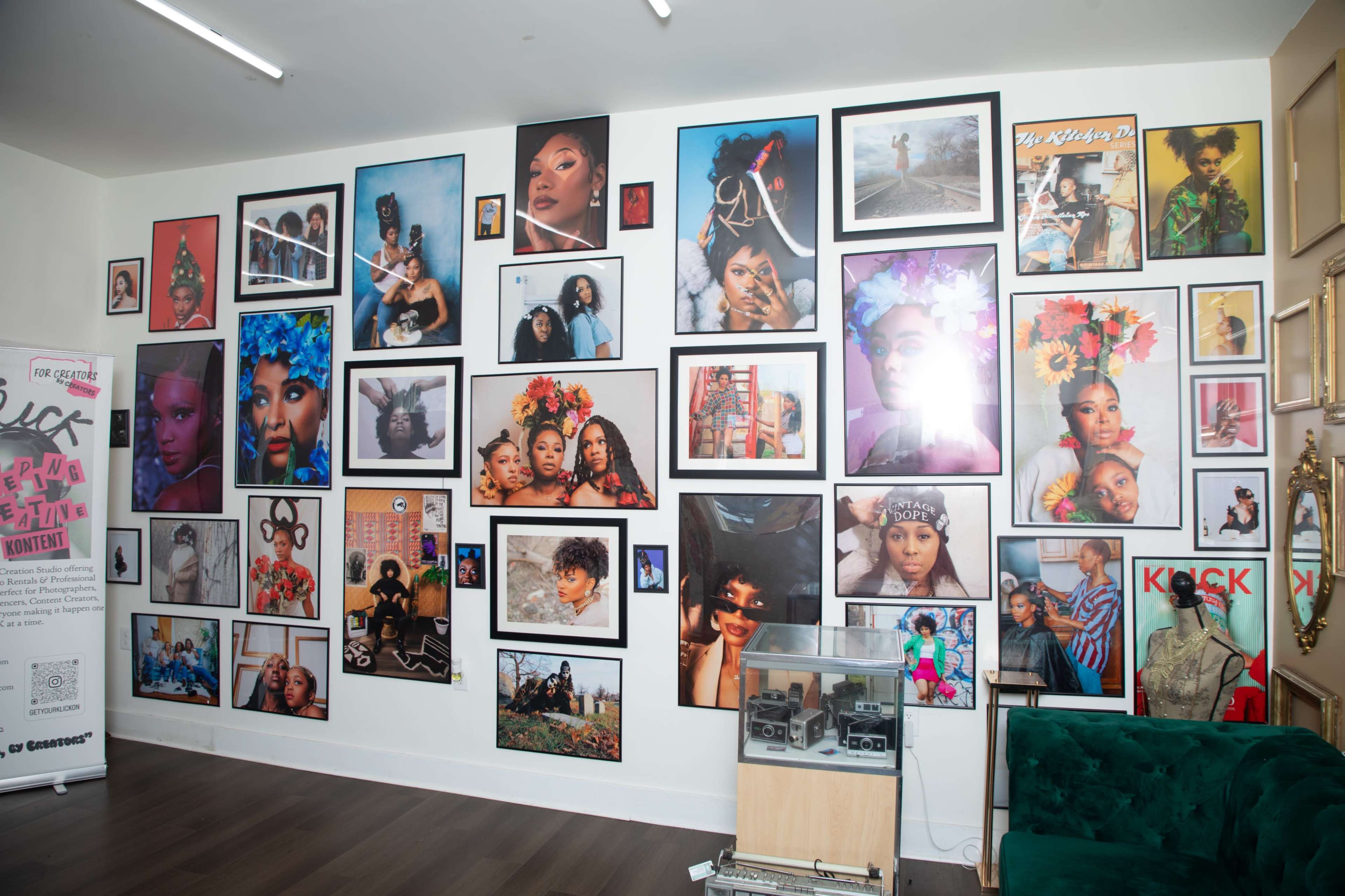 The image shows a wall adorned with various framed photographs, featuring diverse portraits of individuals and artistic displays.