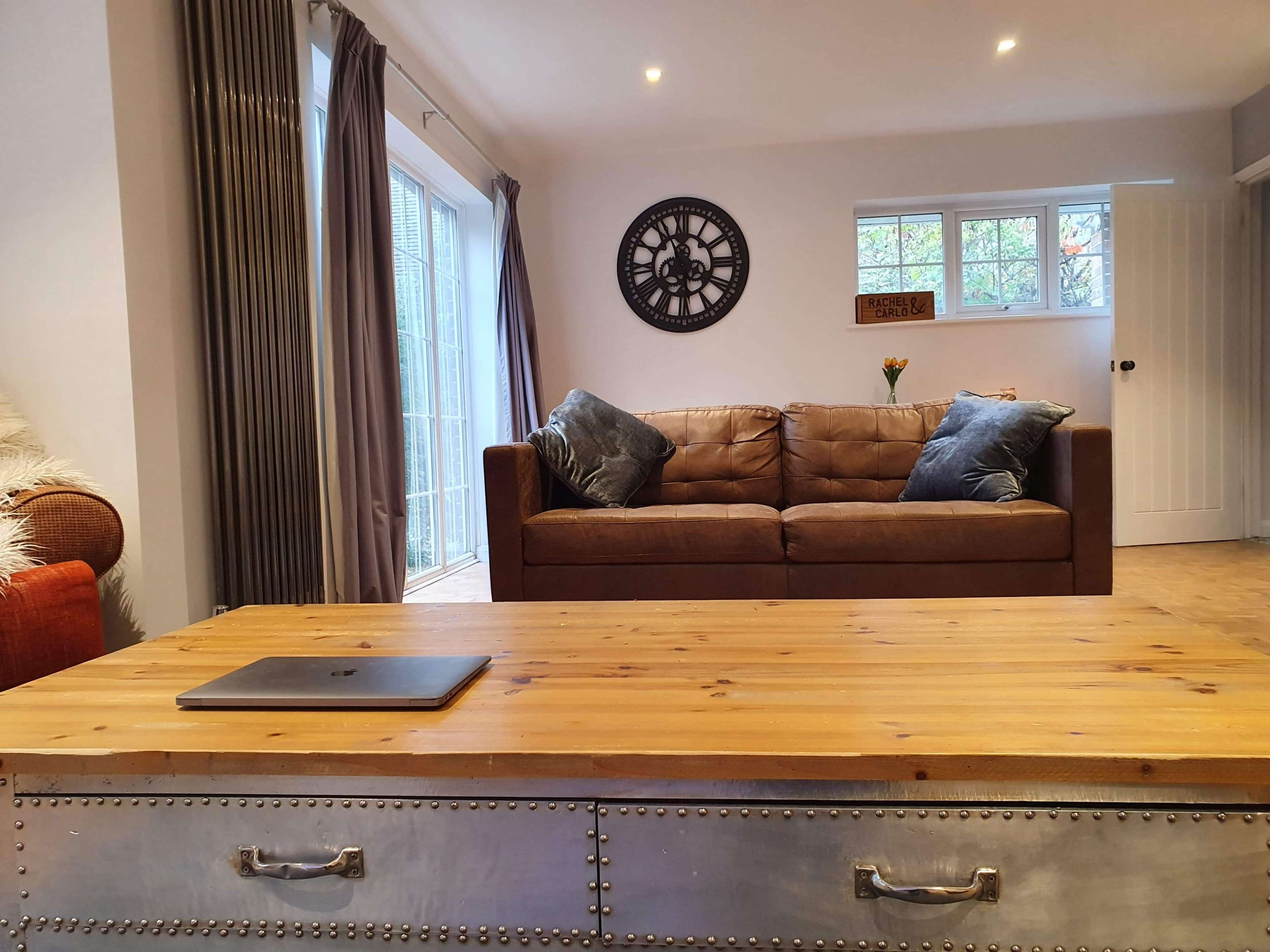 A living room with a brown leather sofa, a wooden coffee table, and glass doors leading to a patio.