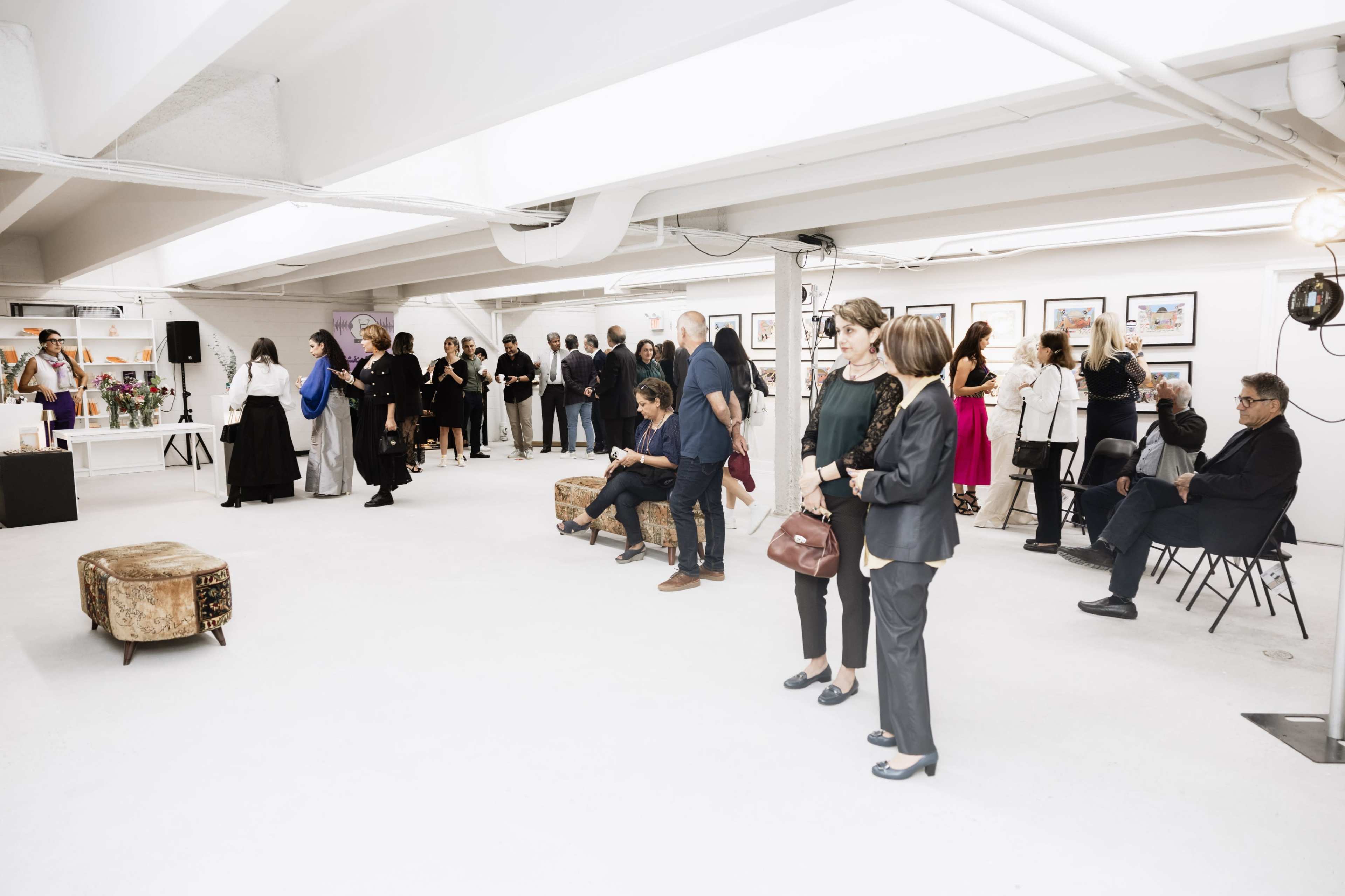 A group of people attends an event in a spacious gallery with photographs displayed on the walls.
