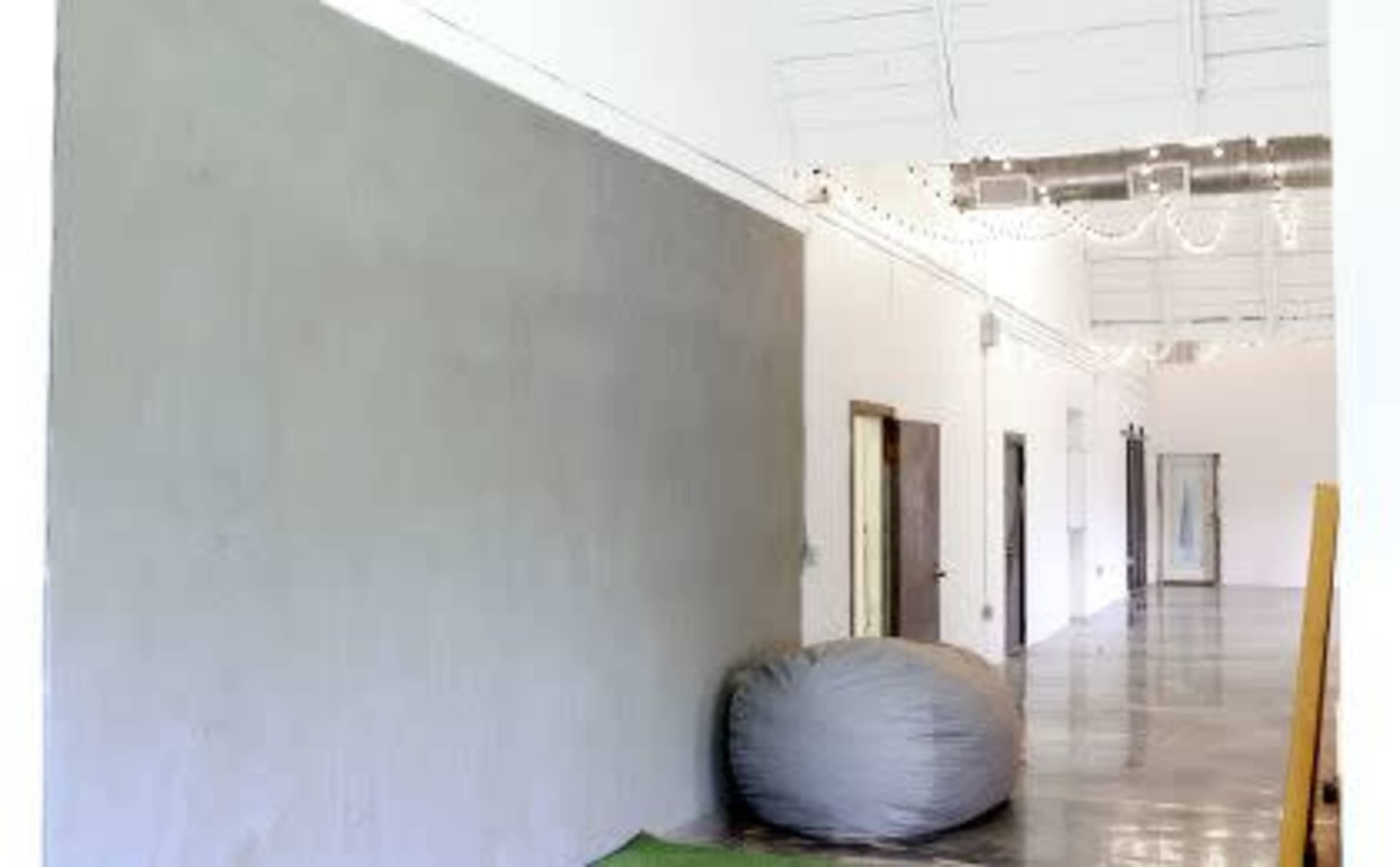 A long, narrow hallway with a smooth gray wall on one side and several doors along the opposite wall.