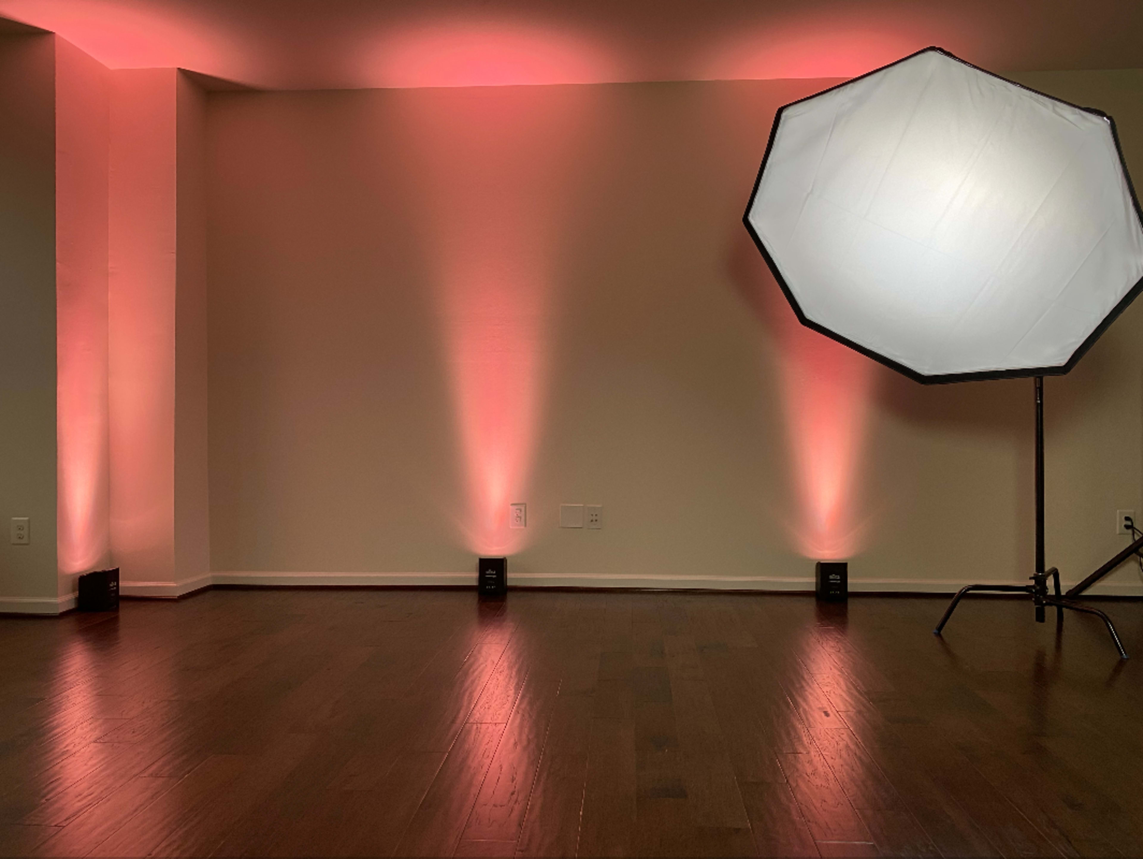 A room with red light accents and a large softbox positioned on one side.