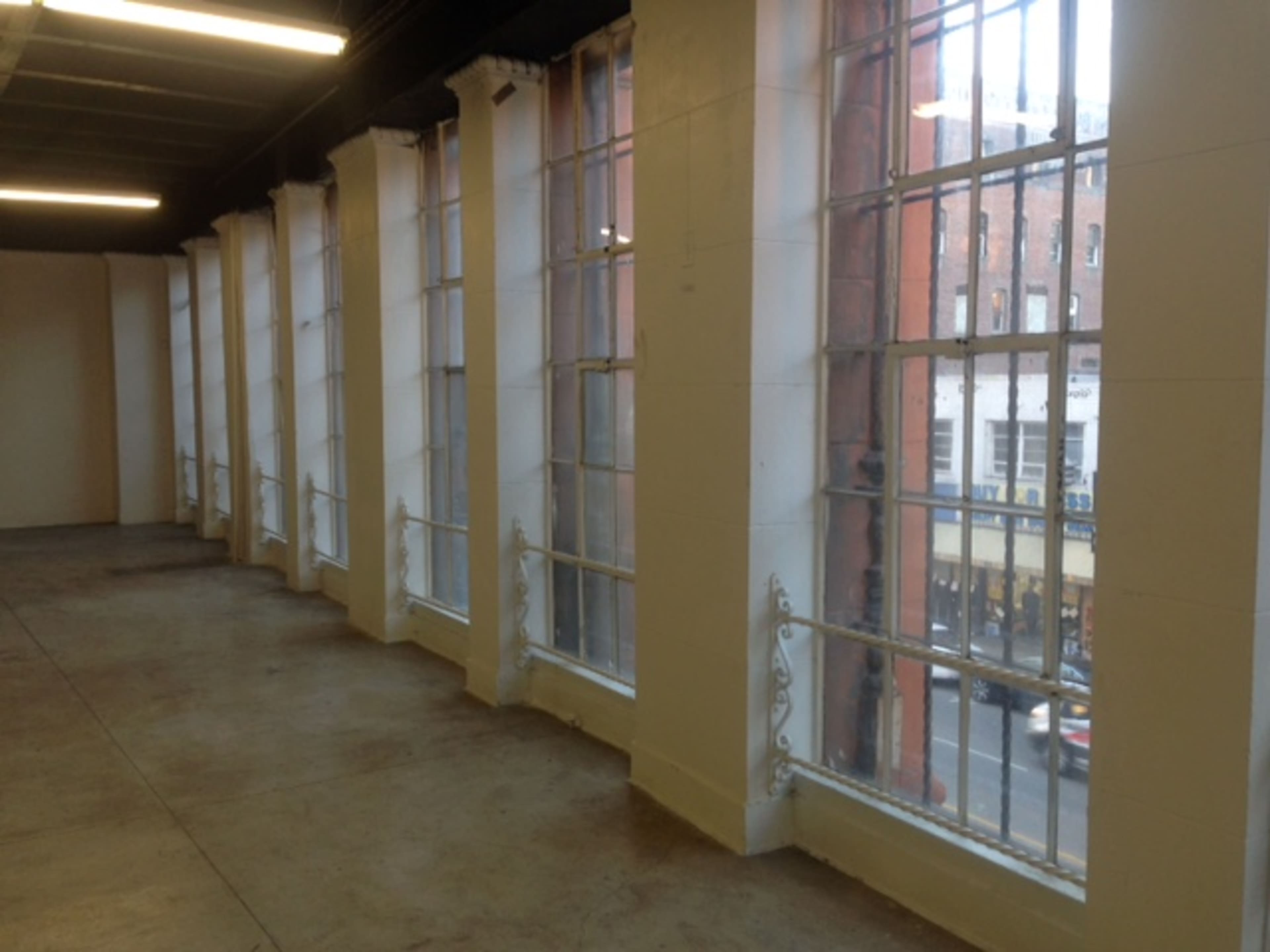 A spacious room with large windows along one wall, allowing natural light to enter.