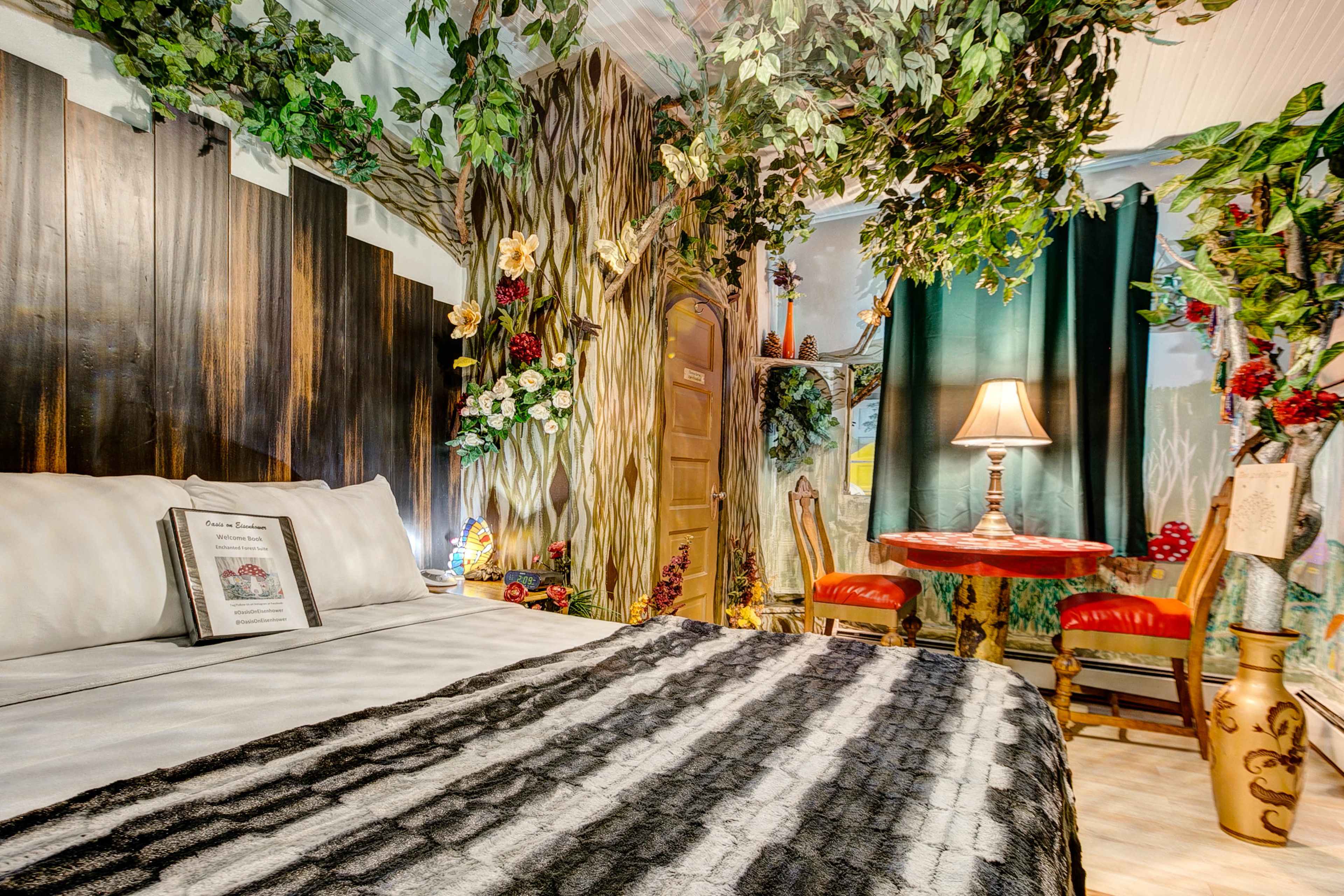 A uniquely decorated bedroom with a tree-themed mural, a wooden door, and a small dining table surrounded by chairs.