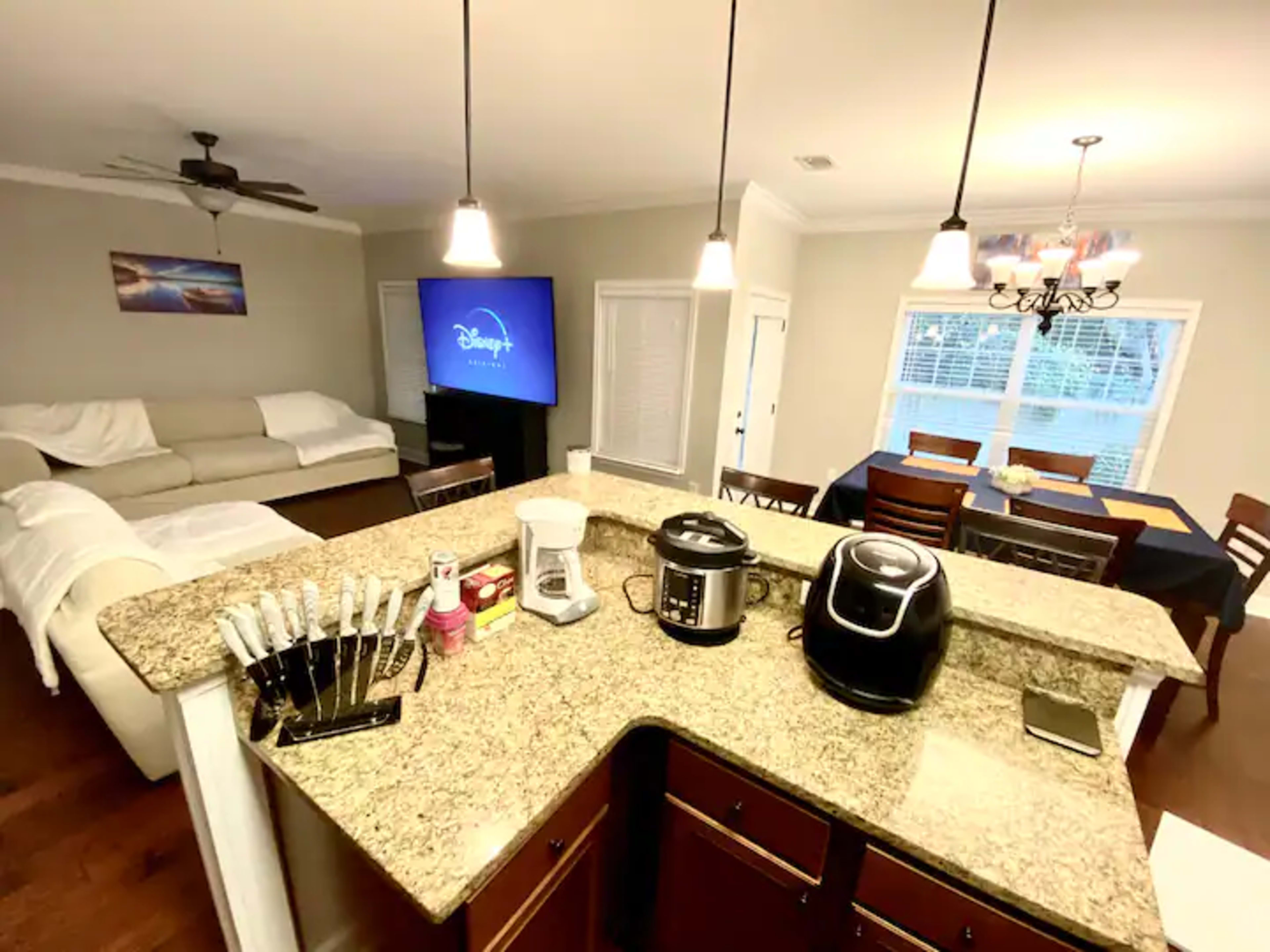 A modern kitchen with granite countertops, featuring kitchen appliances and a dining area with a table and chairs.