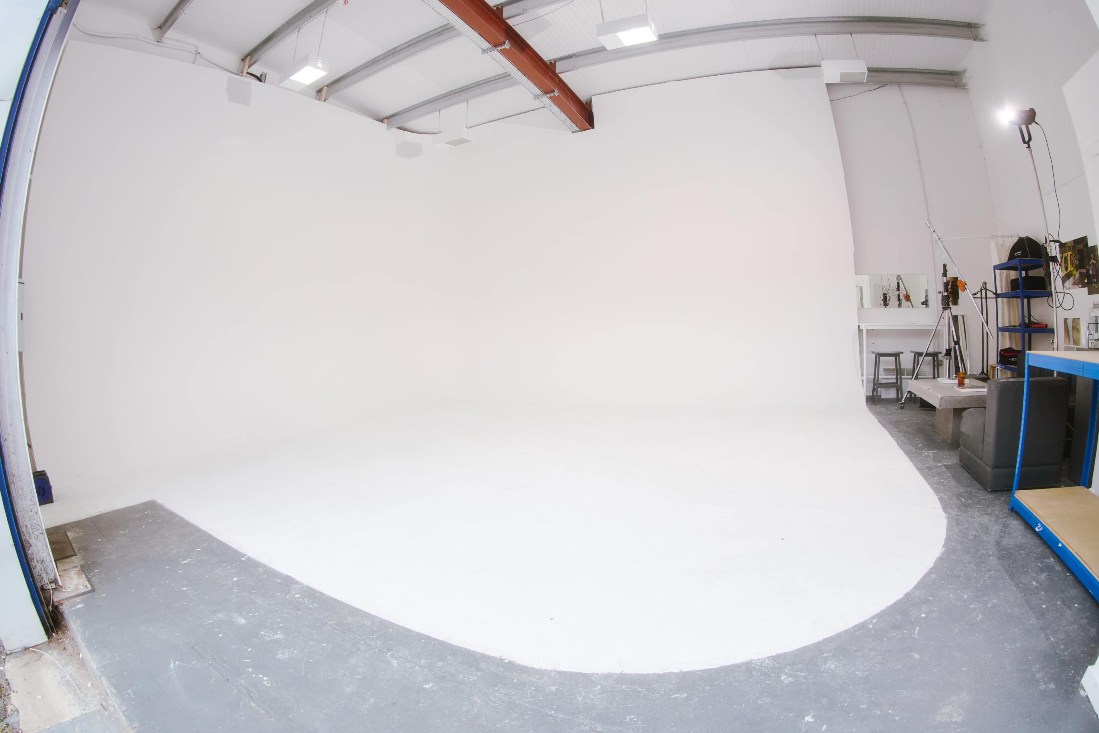 A spacious studio with white walls and a gray floor, featuring minimal equipment and a large open area.
