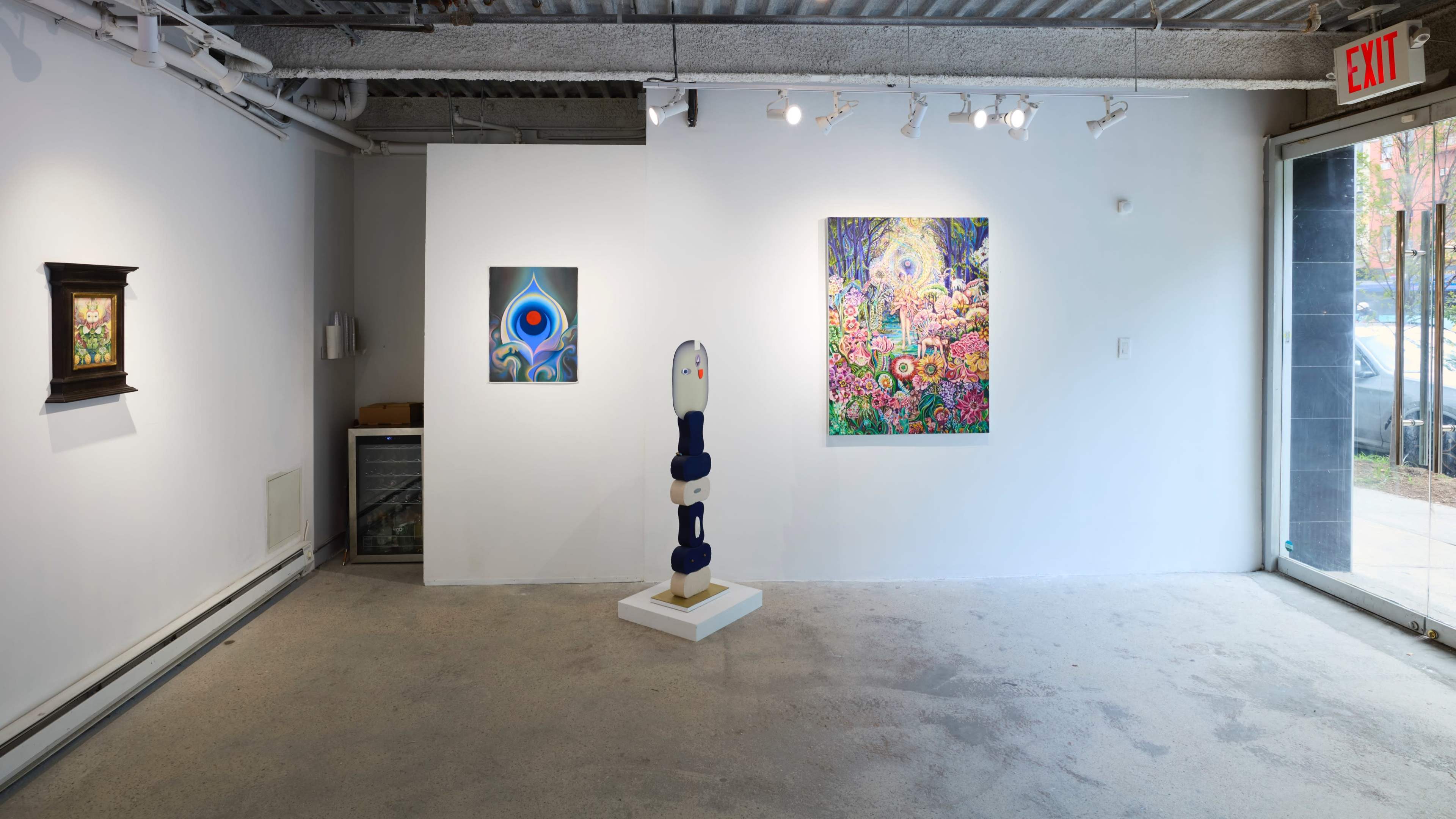 The image shows a modern art gallery featuring a central sculpture, two framed artworks on the walls, and a minimalist interior with concrete floors and bright lighting.