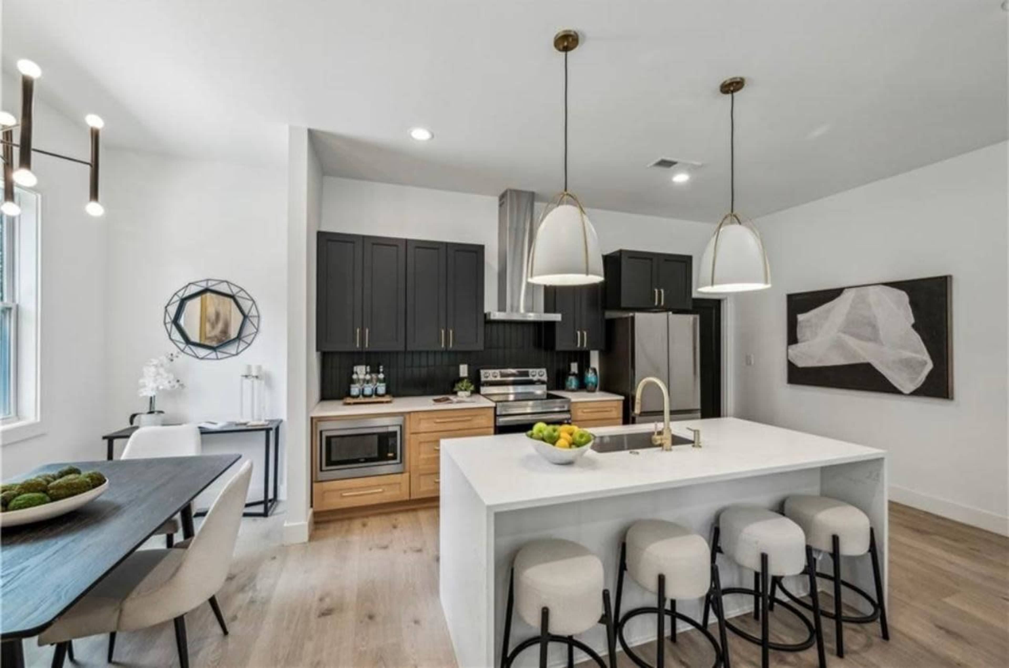 The image shows a modern kitchen with dark cabinets, a white island, and stainless steel appliances.