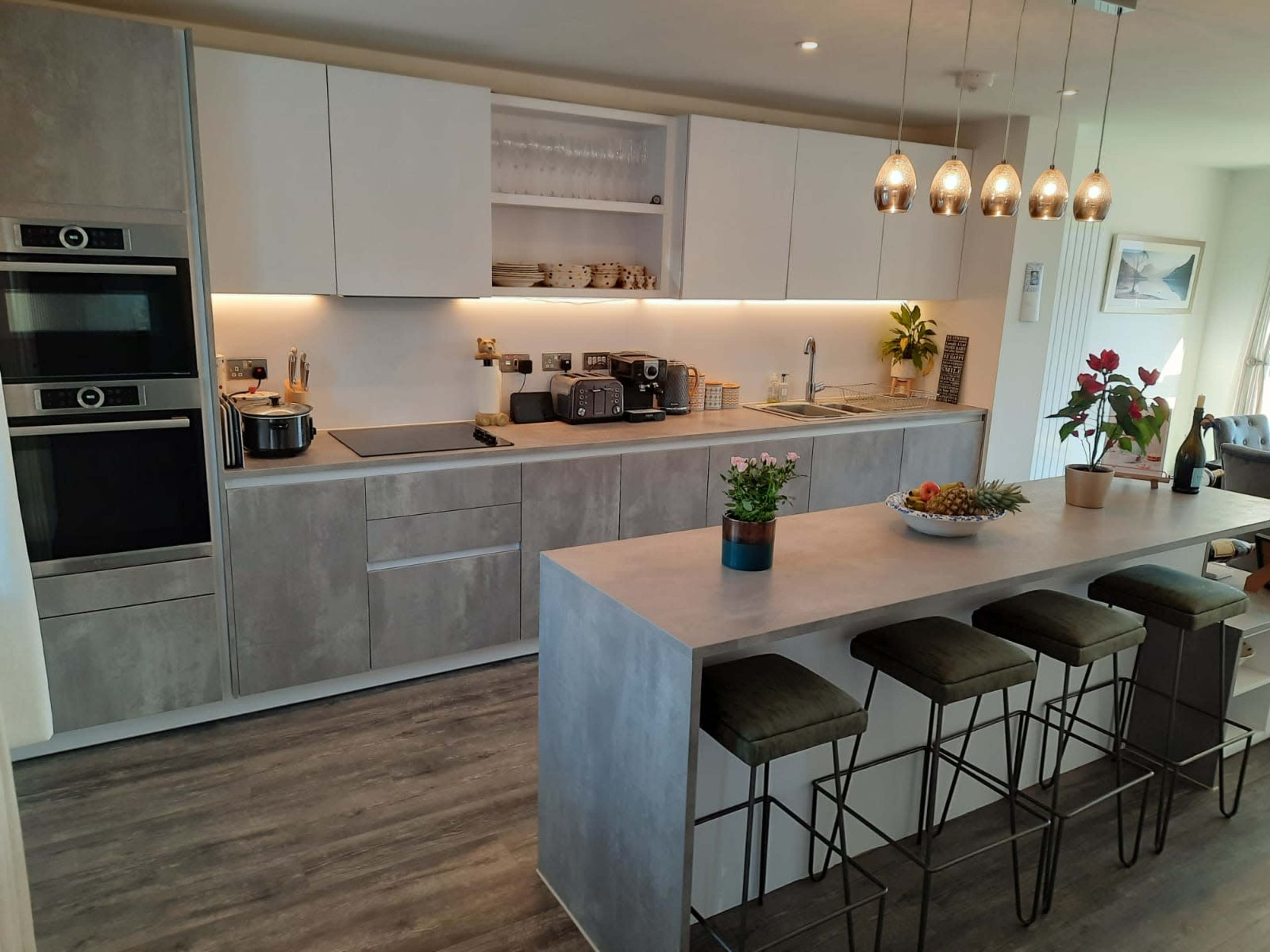 A modern kitchen with sleek cabinetry, integrated appliances, and a central island featuring bar stools.