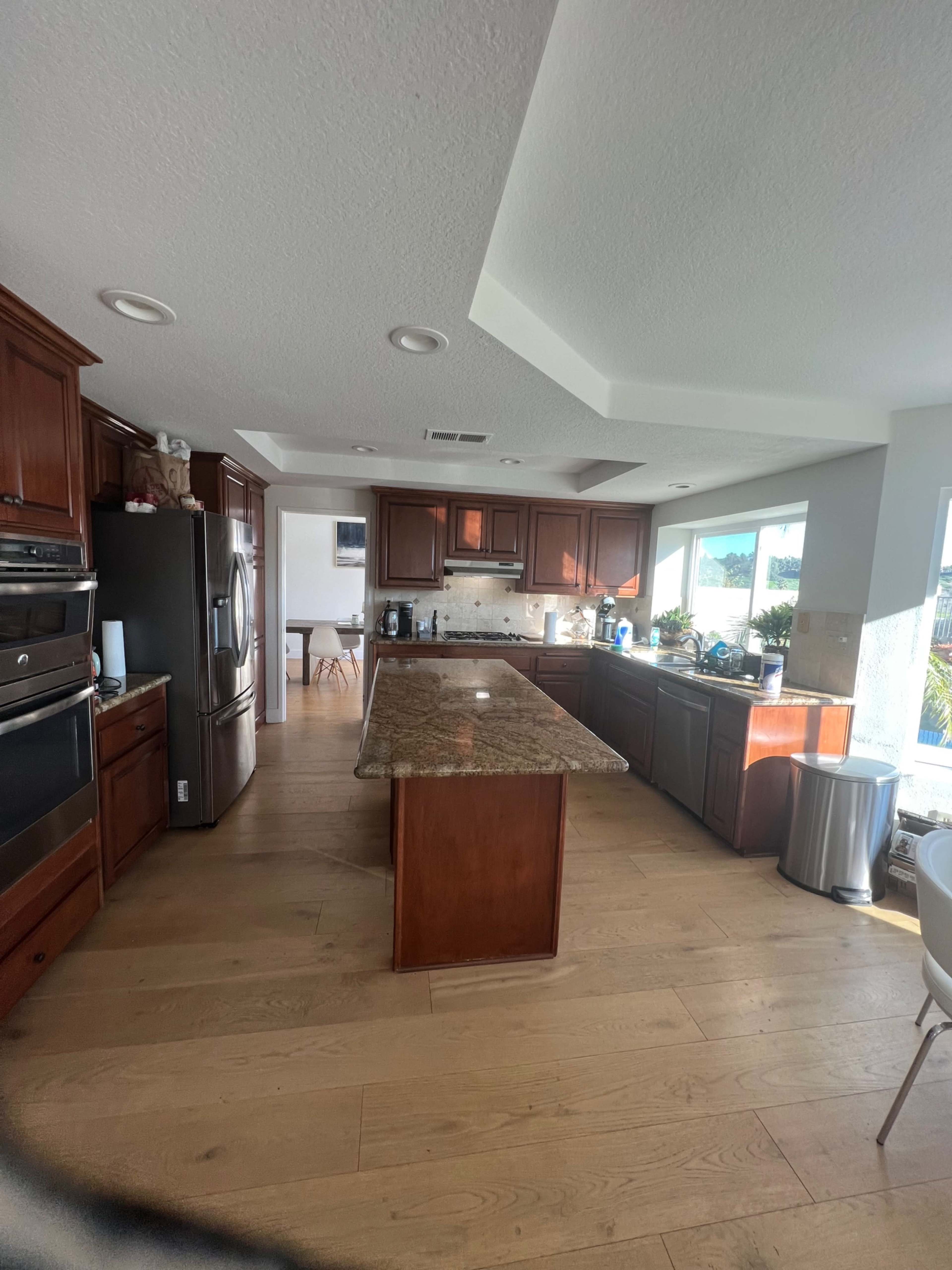 A spacious kitchen with wooden cabinets, a central island, and large windows providing natural light.
